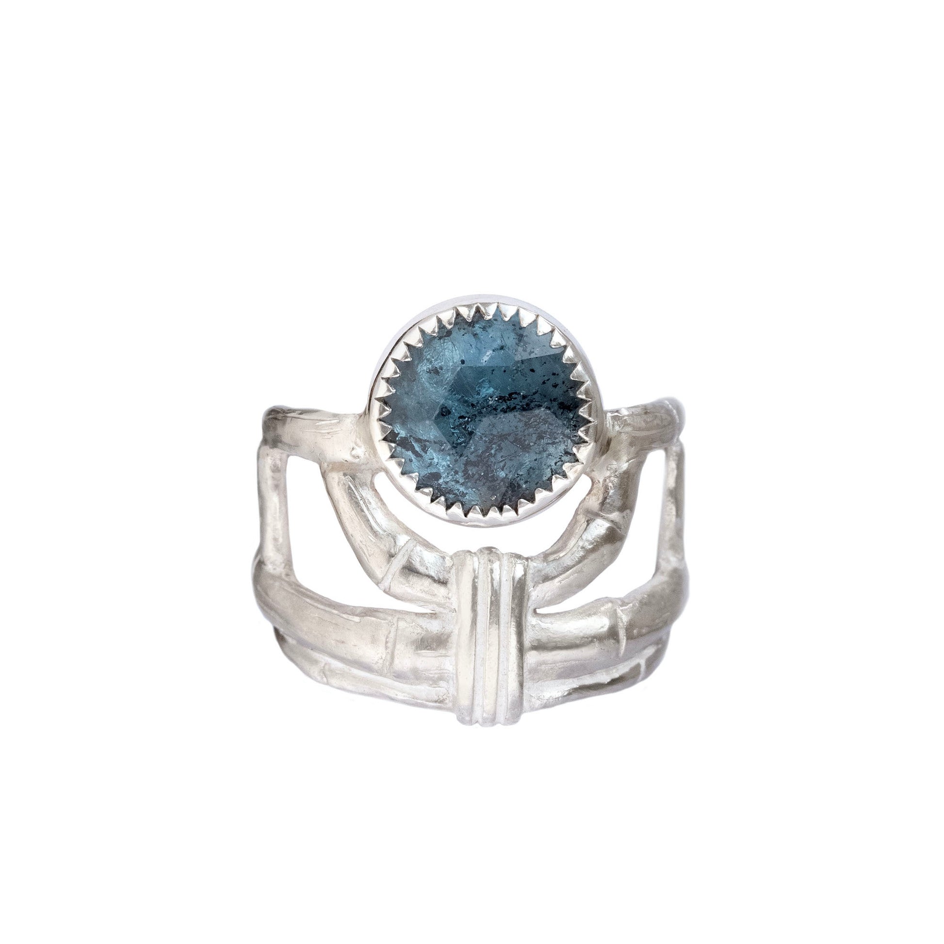 structural open-work ring in a bamboo style, featuring a faceted round teal blue Kyanite gemstone in a serrated setting. Sterling Silver. white background