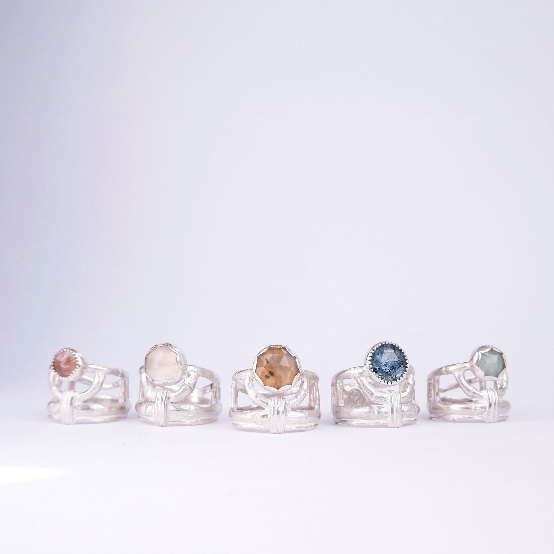 A group of 5 structural open-work ring in a bamboo style, each featuring a different round gemstone. Sterling Silver.