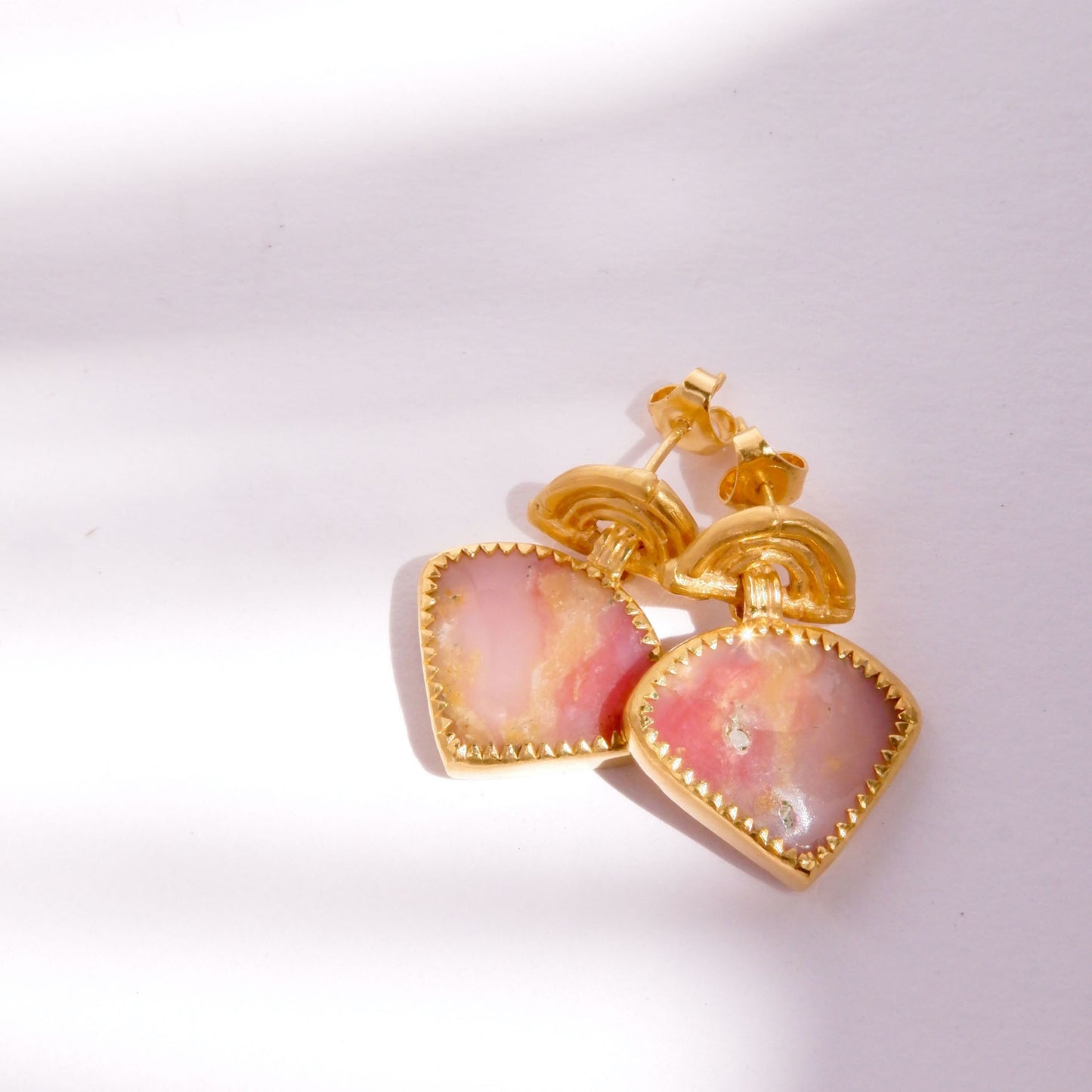 small stud earrings in gold vermeil, featuring triple arches of bamboo, hung with triangular pink opal gemstone charm pendants, set with gold teeth.