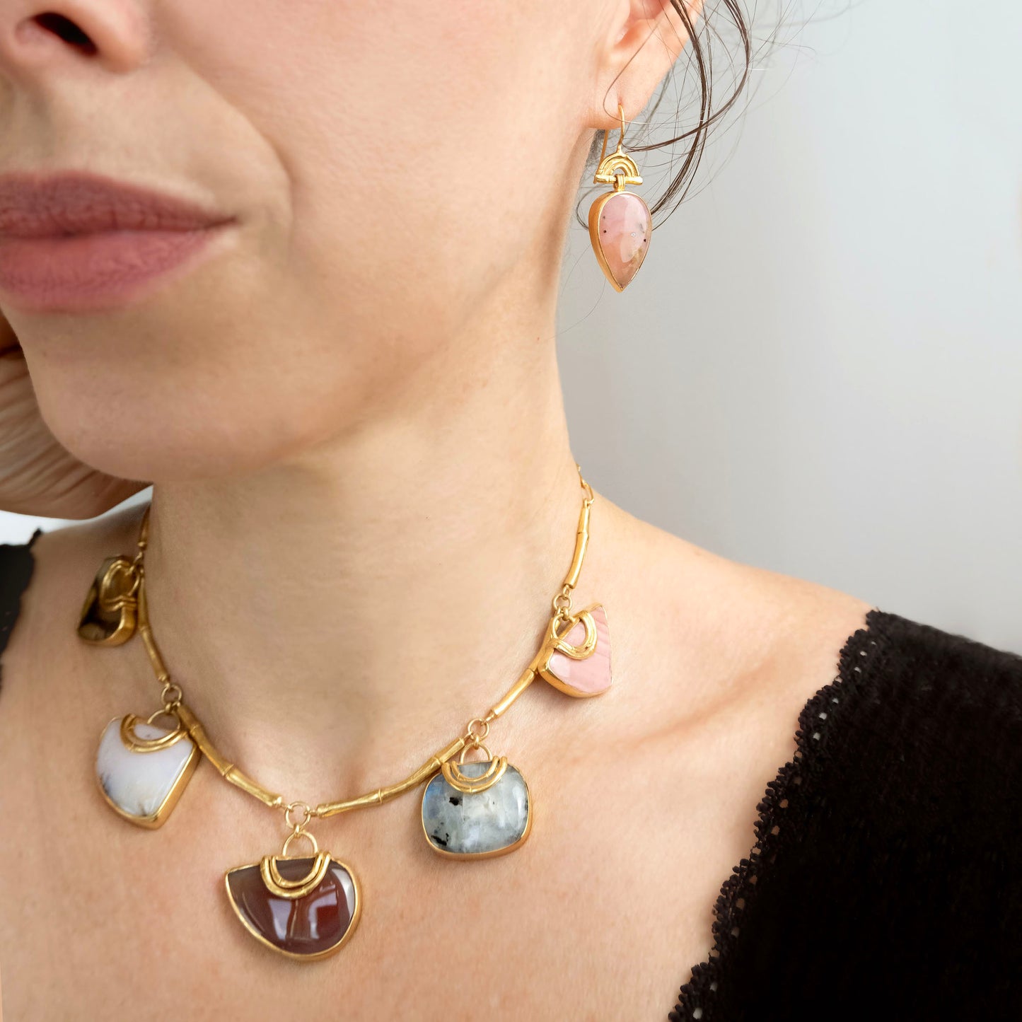 drop earrings in gold vermeil, featuring triple arches of bamboo on hooks, hung with pear/teardrop shaped pink opal gemstone pendants, shown on model