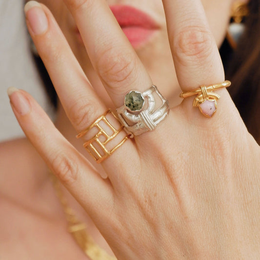structural open-work ring in a bamboo style, featuring a faceted round green rutilated Prehnite gemstone in a scalloped setting. Sterling Silver. Shown on hand for scale, with 2 gold bamboo rings