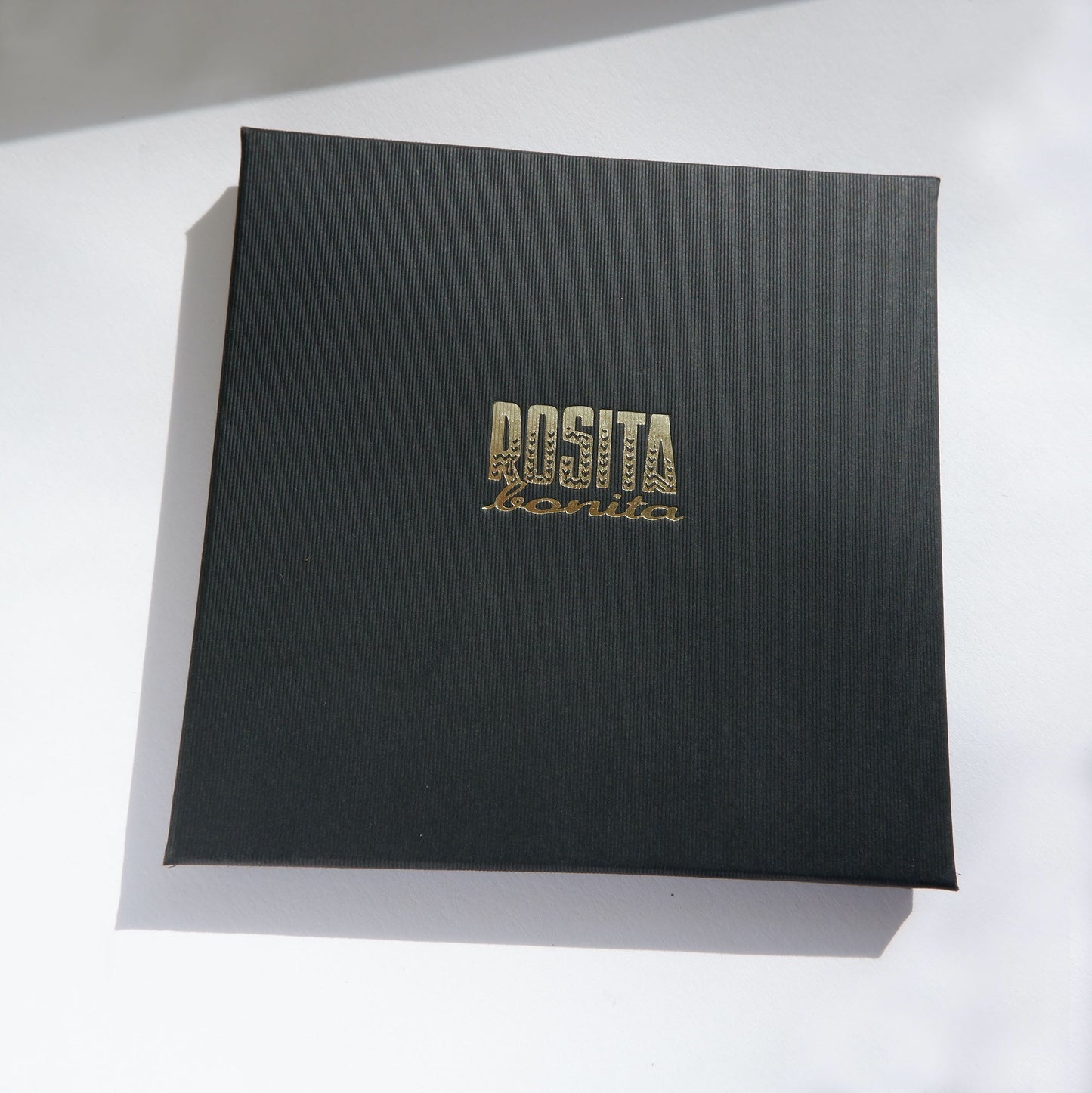 Black pinstripe cardboard jewellery box with Rosita Bonita logo in gold