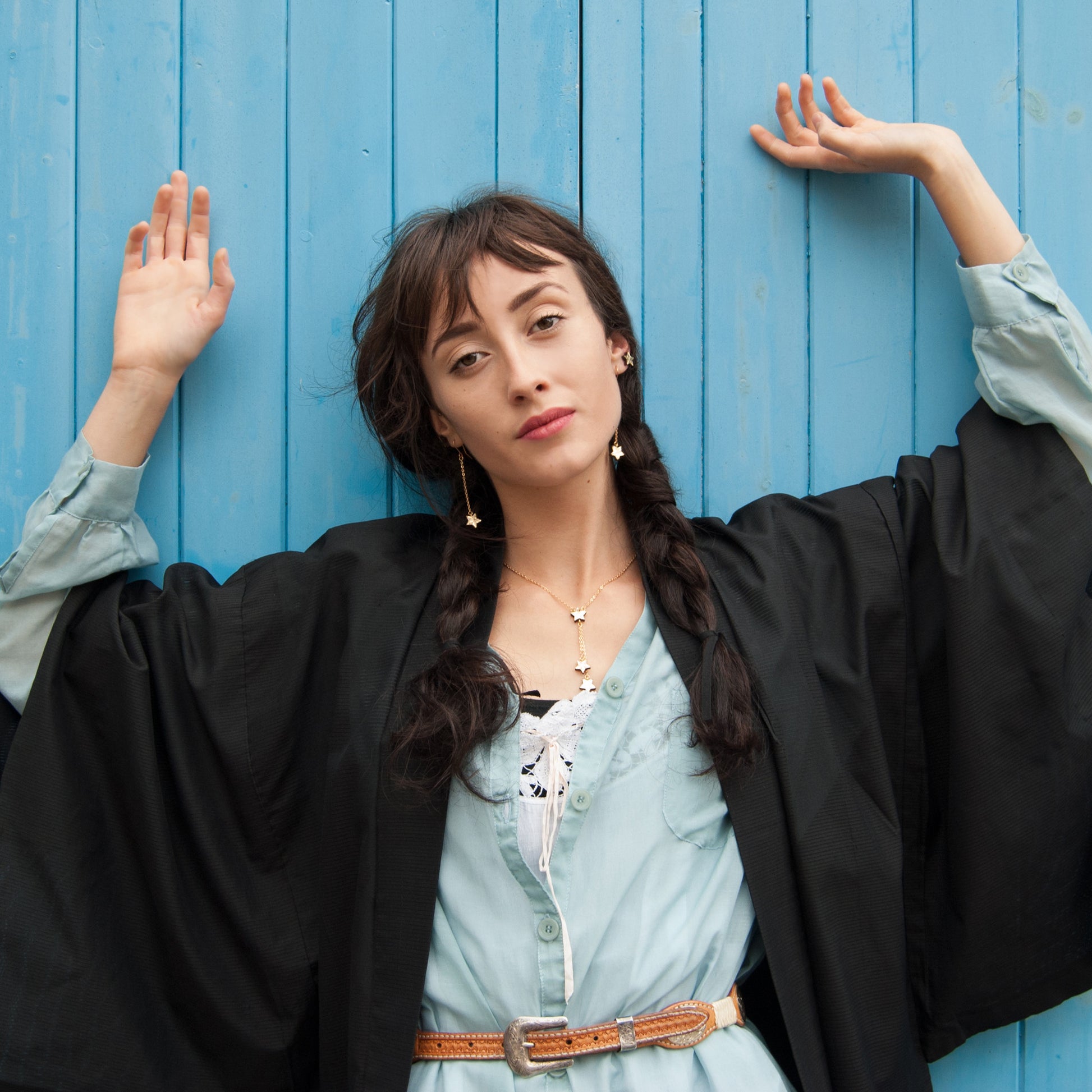 model styled in westernwear on blue clapboard background with gold star jewellery