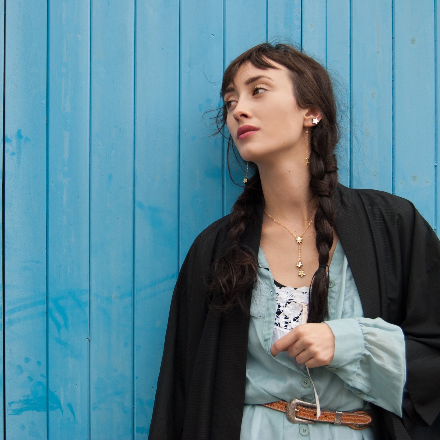 model styled in westernwear on blue clapboard background with gold star jewellery