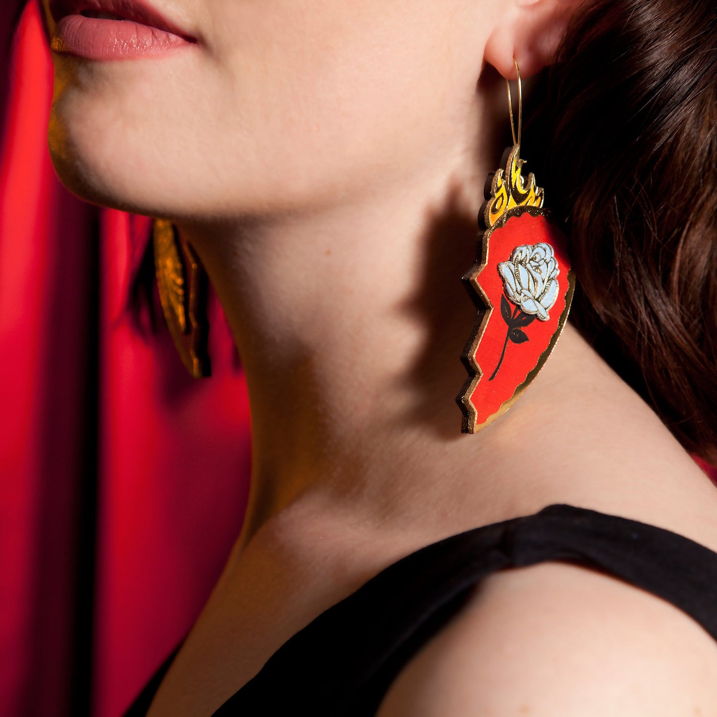 red leather broken heart pendants & earrings, with golden owls, flames & blue roses on model, close crop