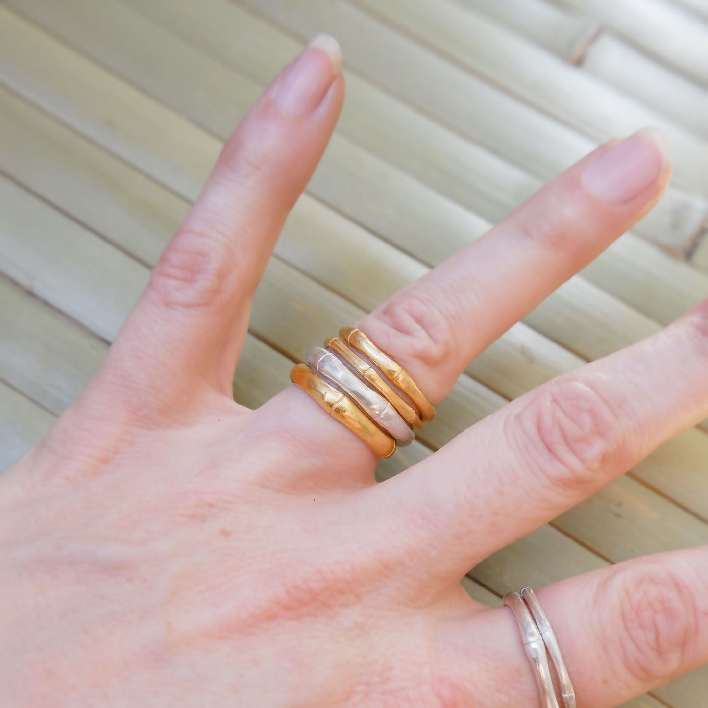 Hand wearing stacked bamboo style rings, in three thicknesses in Sterling Silver & Gold Vermeil