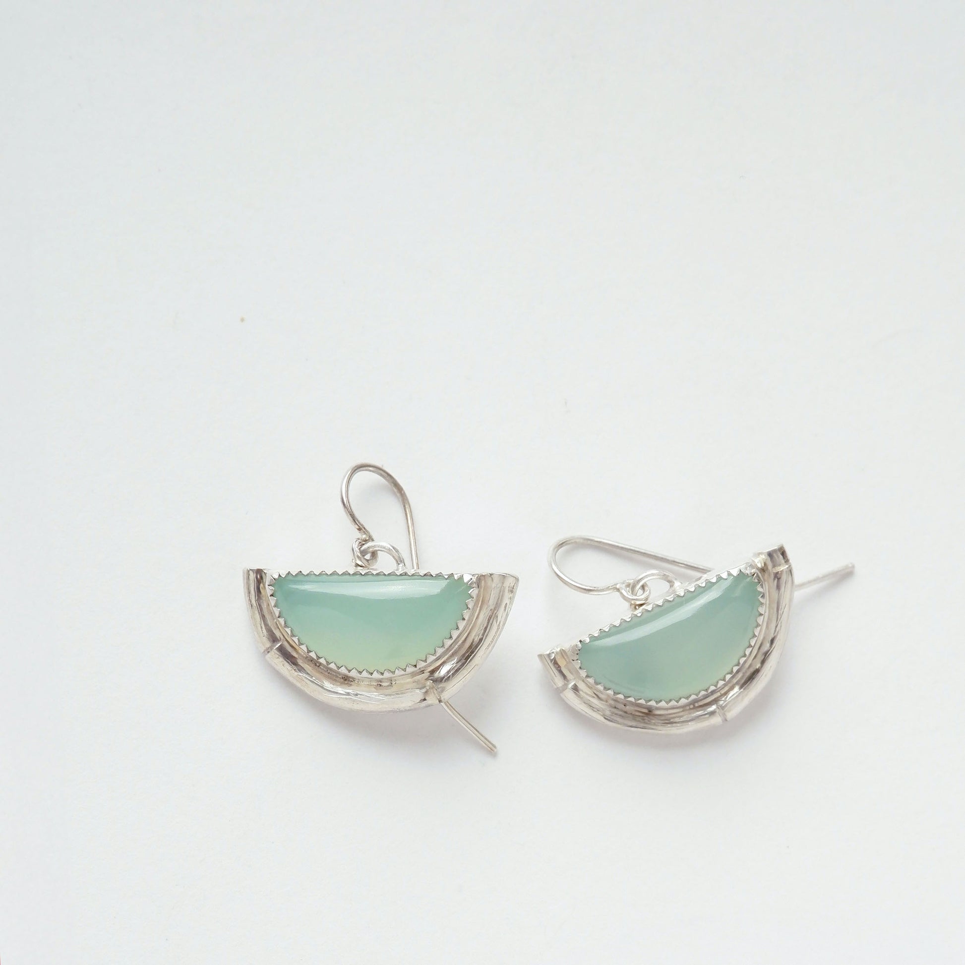 Earrings featuring half moon shaped semi precious aqua blue chalcedony gemstones,  cupped by solid silver bamboo hammock, with simple wire ear hooks.