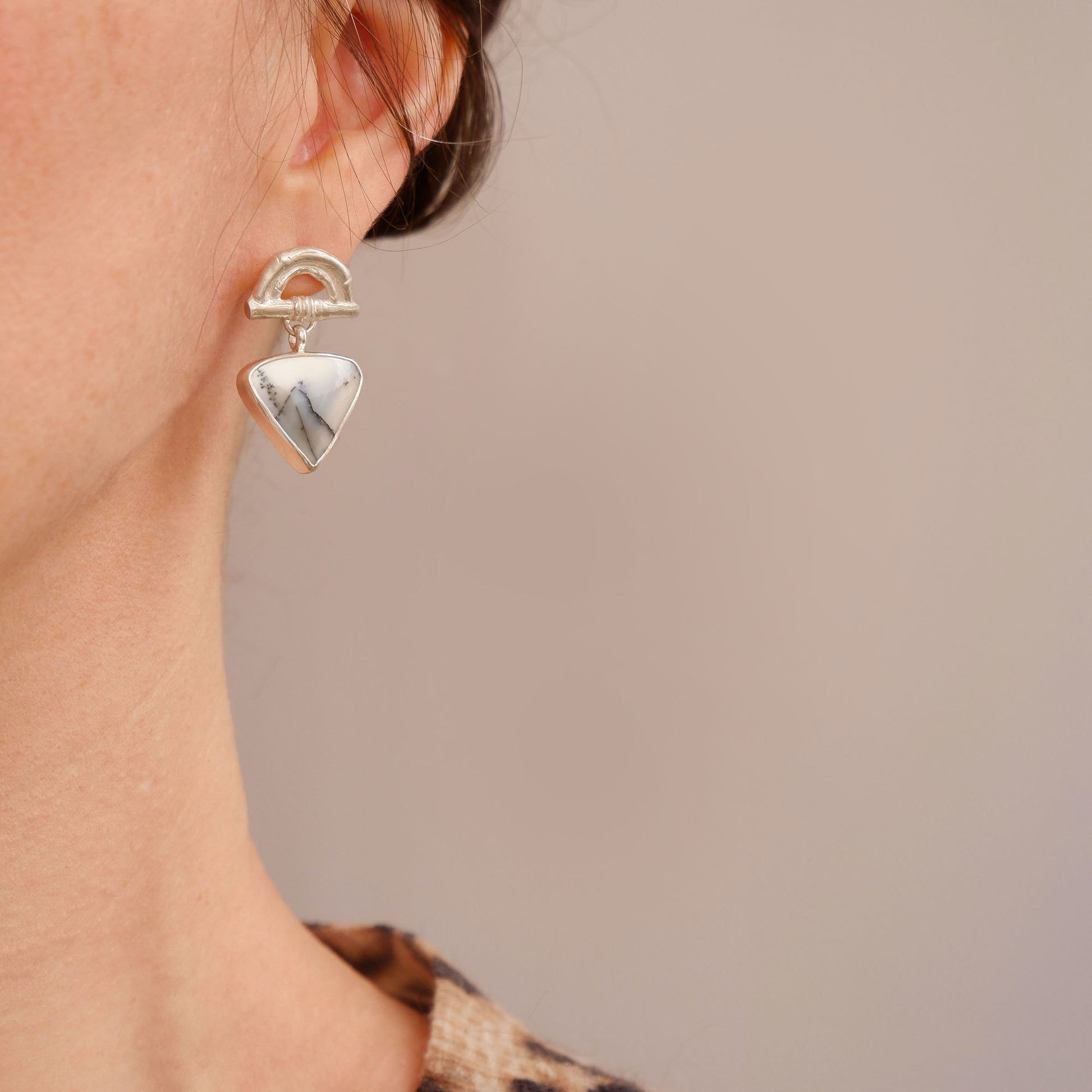 Sterling Silver stud earrings featuring bamboo sunrise arch design, with gemstone drop pendants in white & grey Dendrite Opal, shown on model