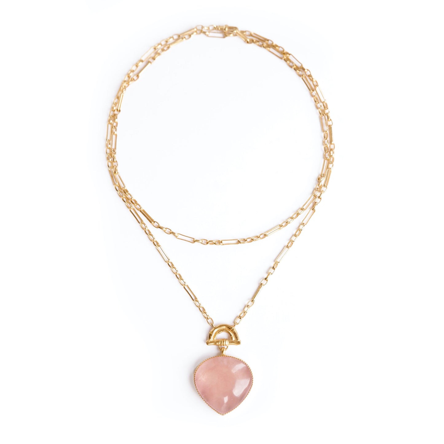 Gold double chain necklace with a rose pink quartz heart-shaped pendant with golden bamboo arch detail, on a white background