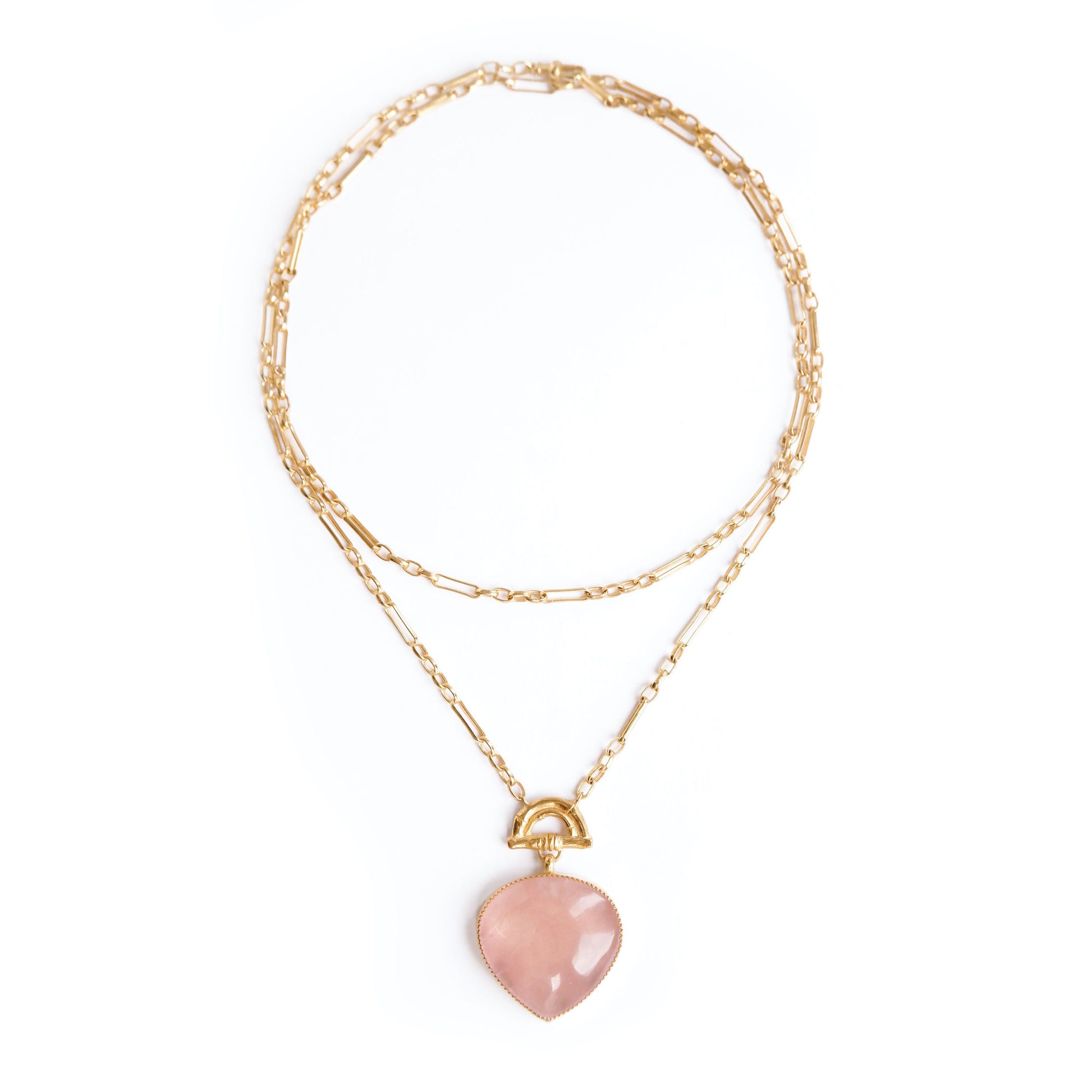 Gold double chain necklace with a rose pink quartz heart-shaped pendant with golden bamboo arch detail, on a white background