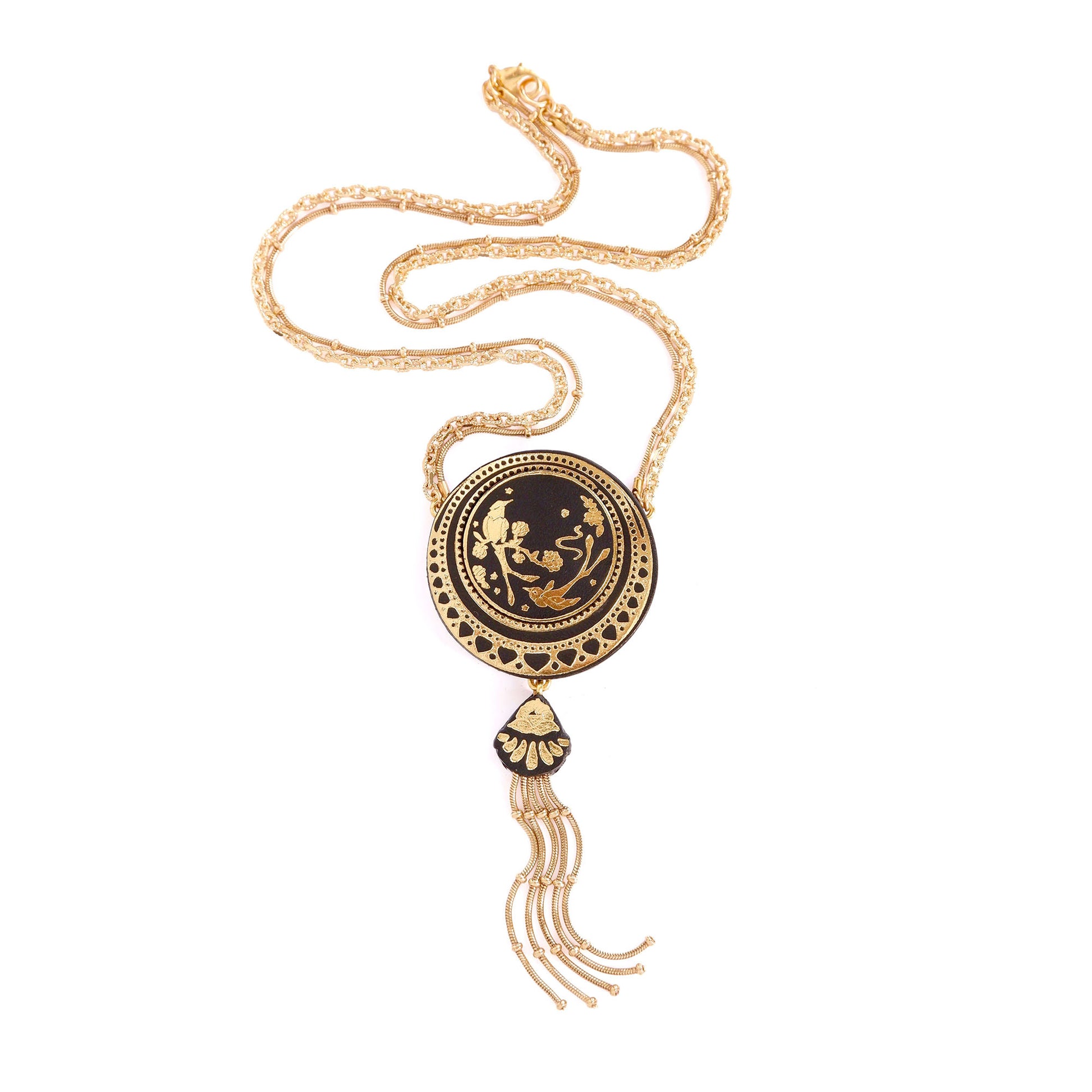 leather medallion pendant necklace, printed with shiny gold foil design of birds & flowers In circle frame, hung from gold plated chain, with gold beaded snake chain tassel. white background.
