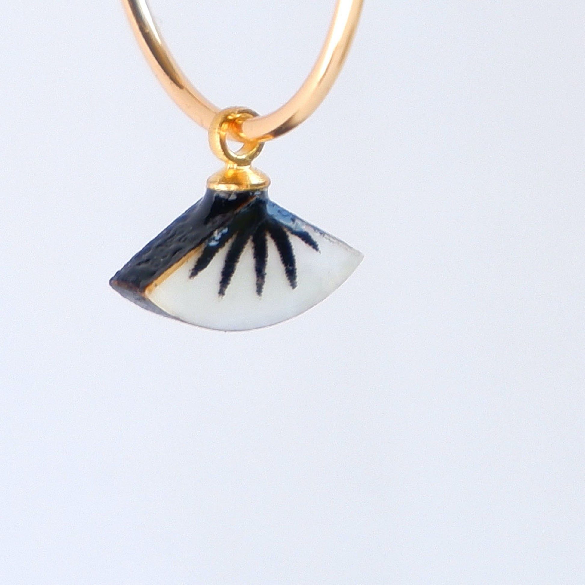 small gold hoop earrings with black spiky palm design on mother of pearl.