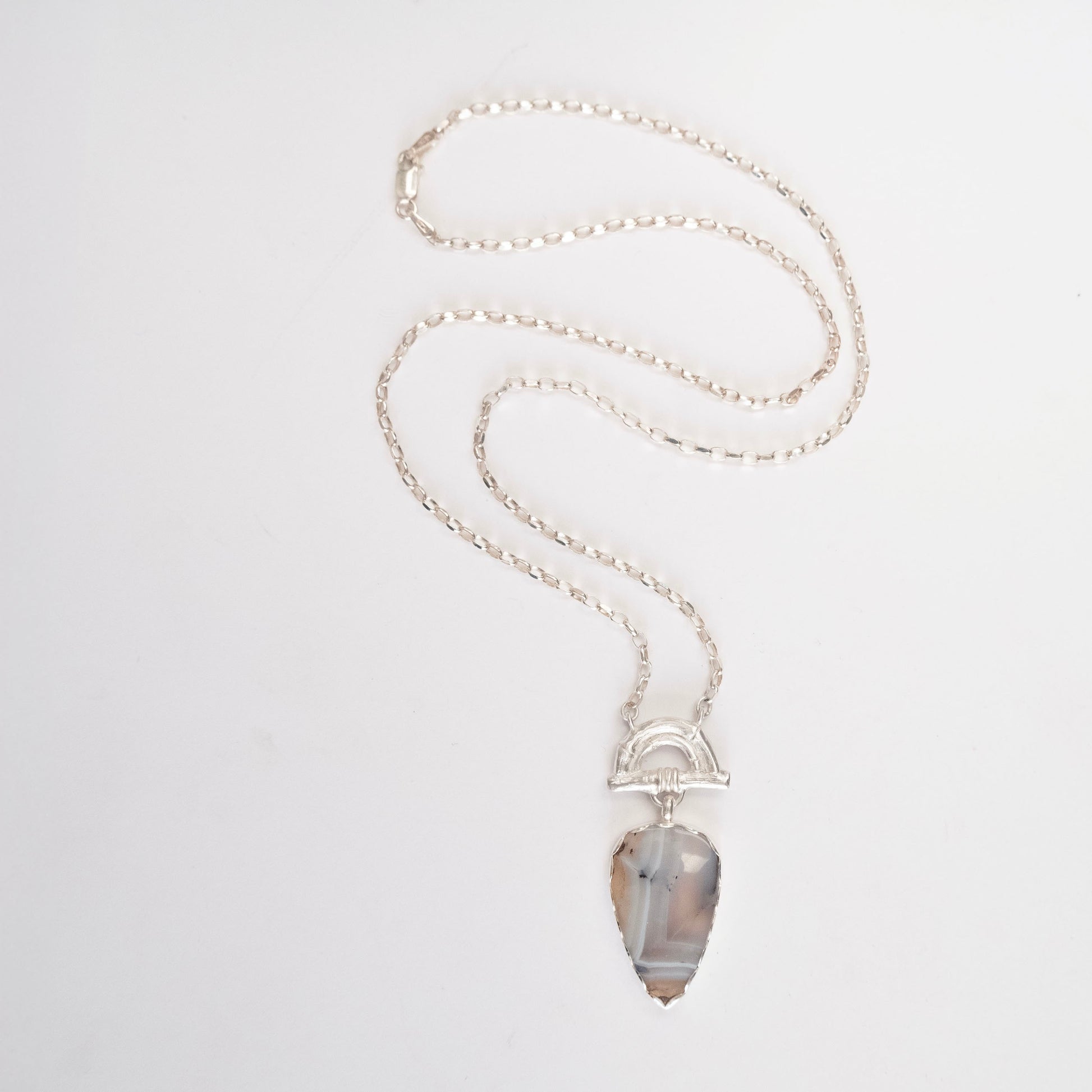 Pendant with pear -shaped pale Montana Agate Gemstone hanging from silver Bamboo Arch, on fine silver chain. white background