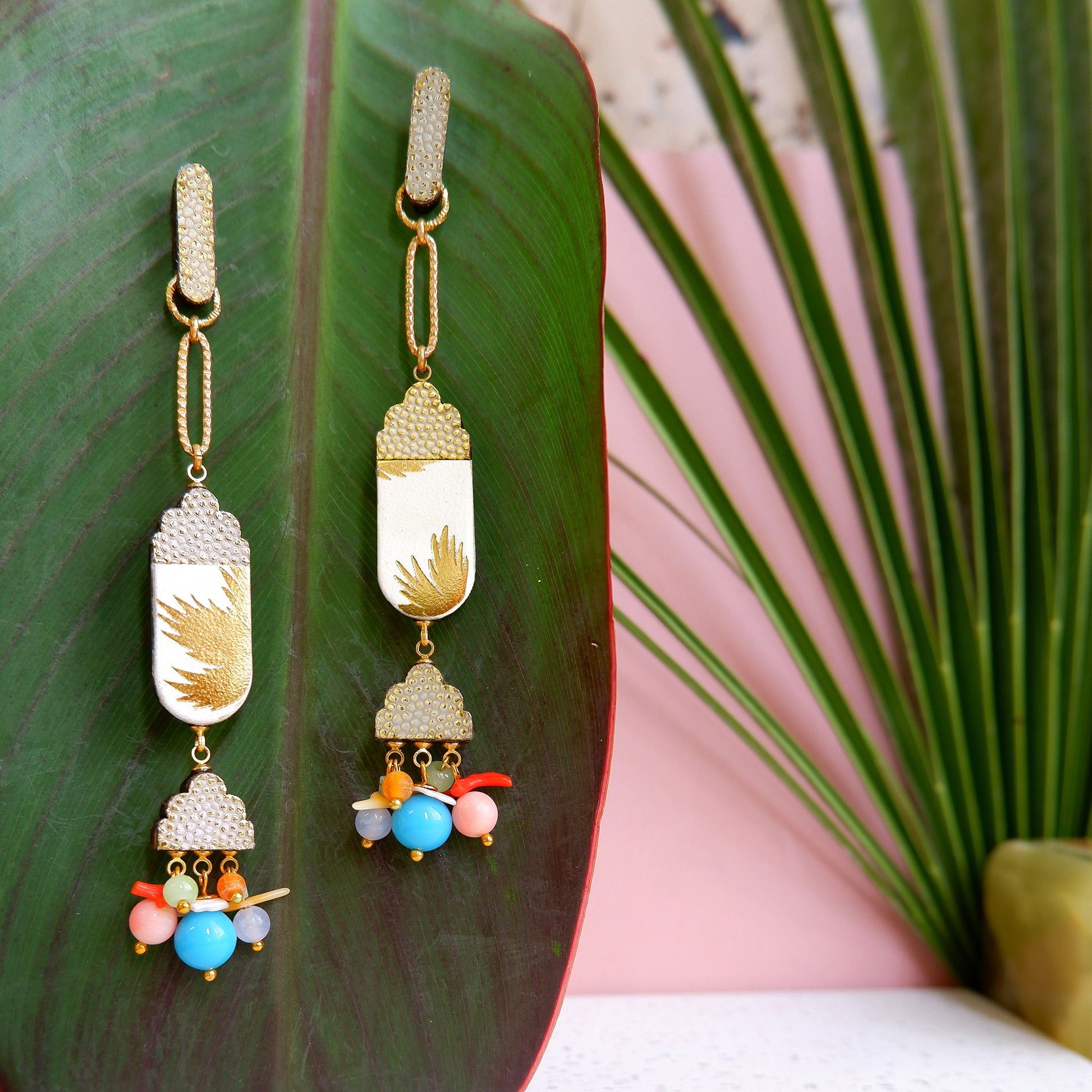 gold palm tree print white leather, & textured gold leather dro earrings, with clusters of rainbow glass & gemstone beads, on a large leaf
