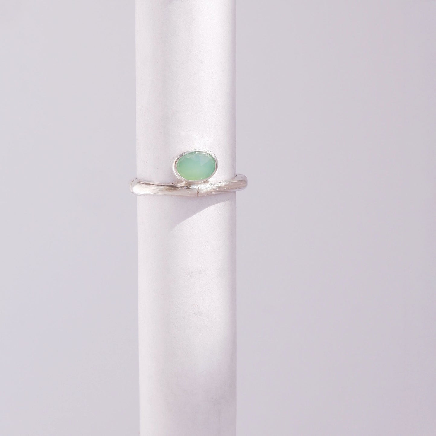 Sterling Silver bamboo style ring with a small oval pale apple green Chrysoprase gem stone, on a white background