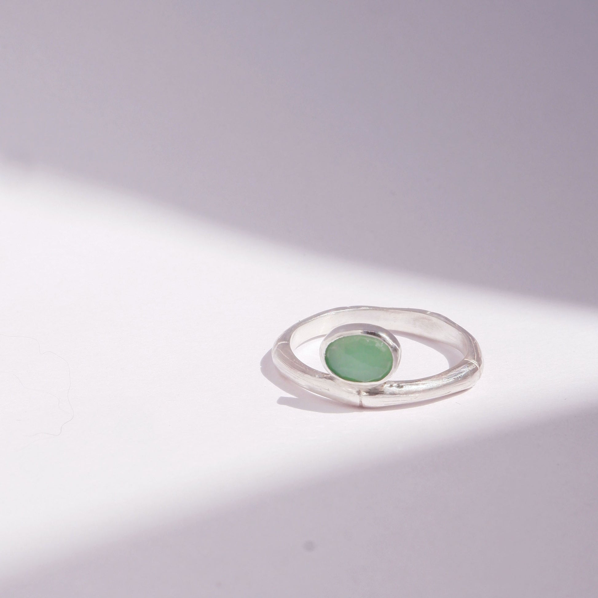 Sterling Silver bamboo style ring with a small oval pale apple green Chrysoprase gem stone, on a white background