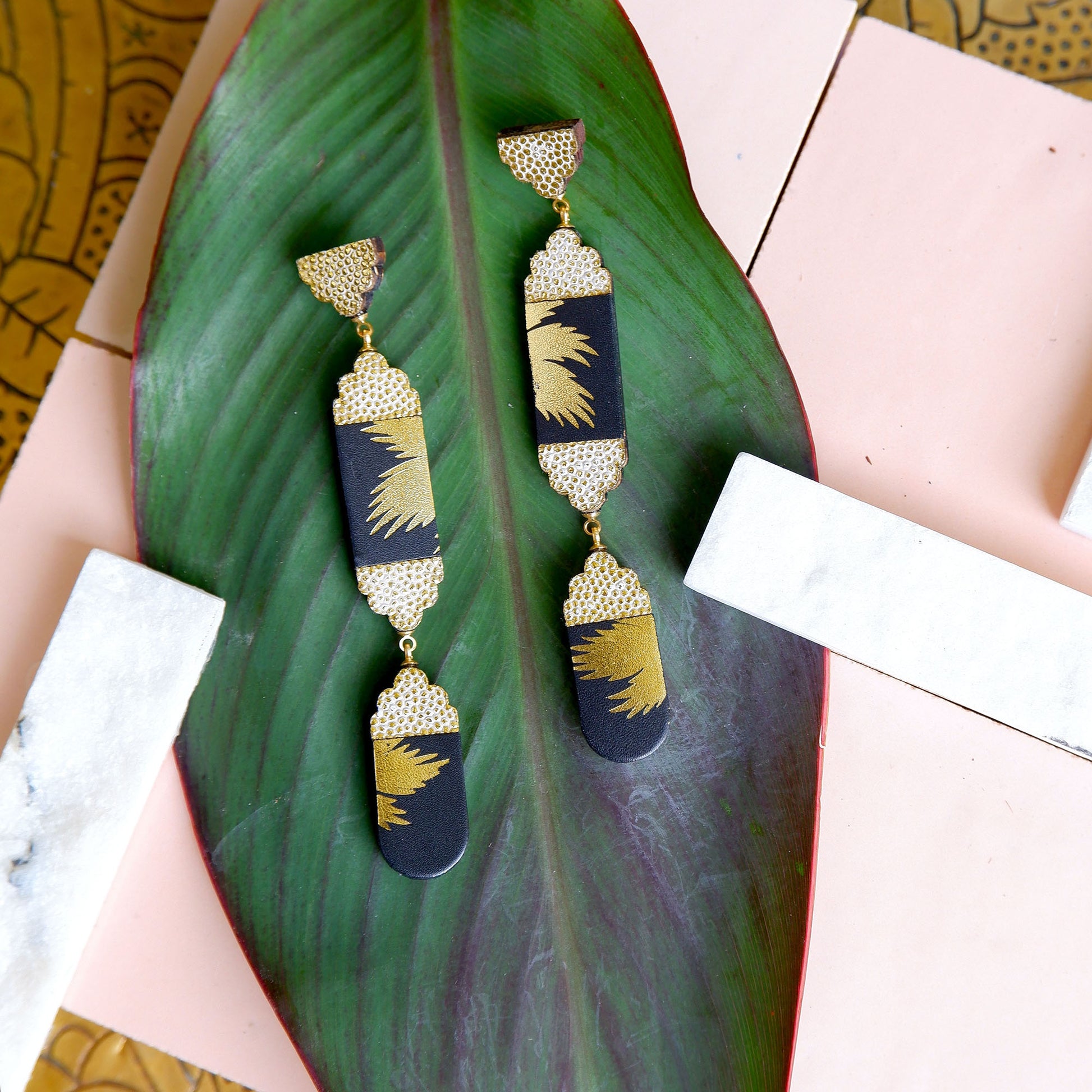 long leather drop earrings with gold palm print & embossed dot pattern, on leaf
