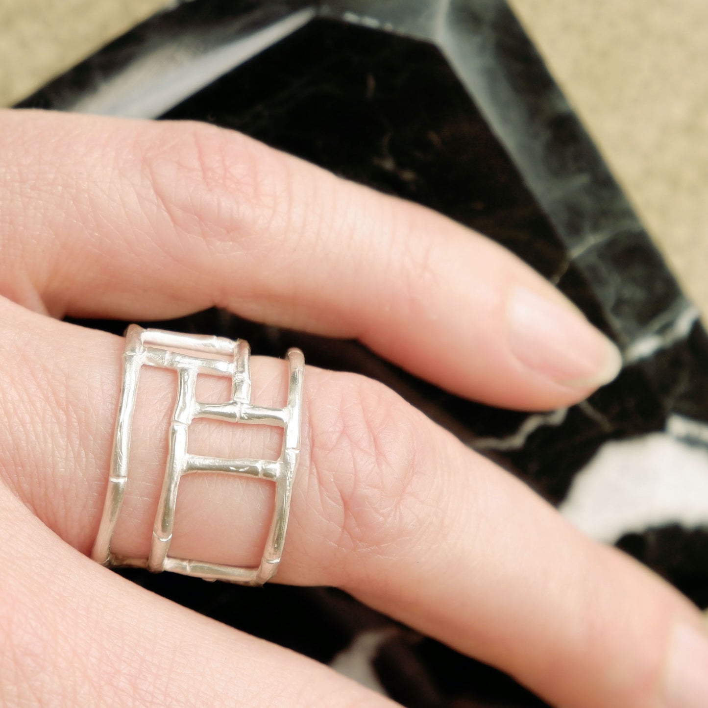 Wide Sterling Silver ring with geometric open-work Bamboo screen design, on a hand