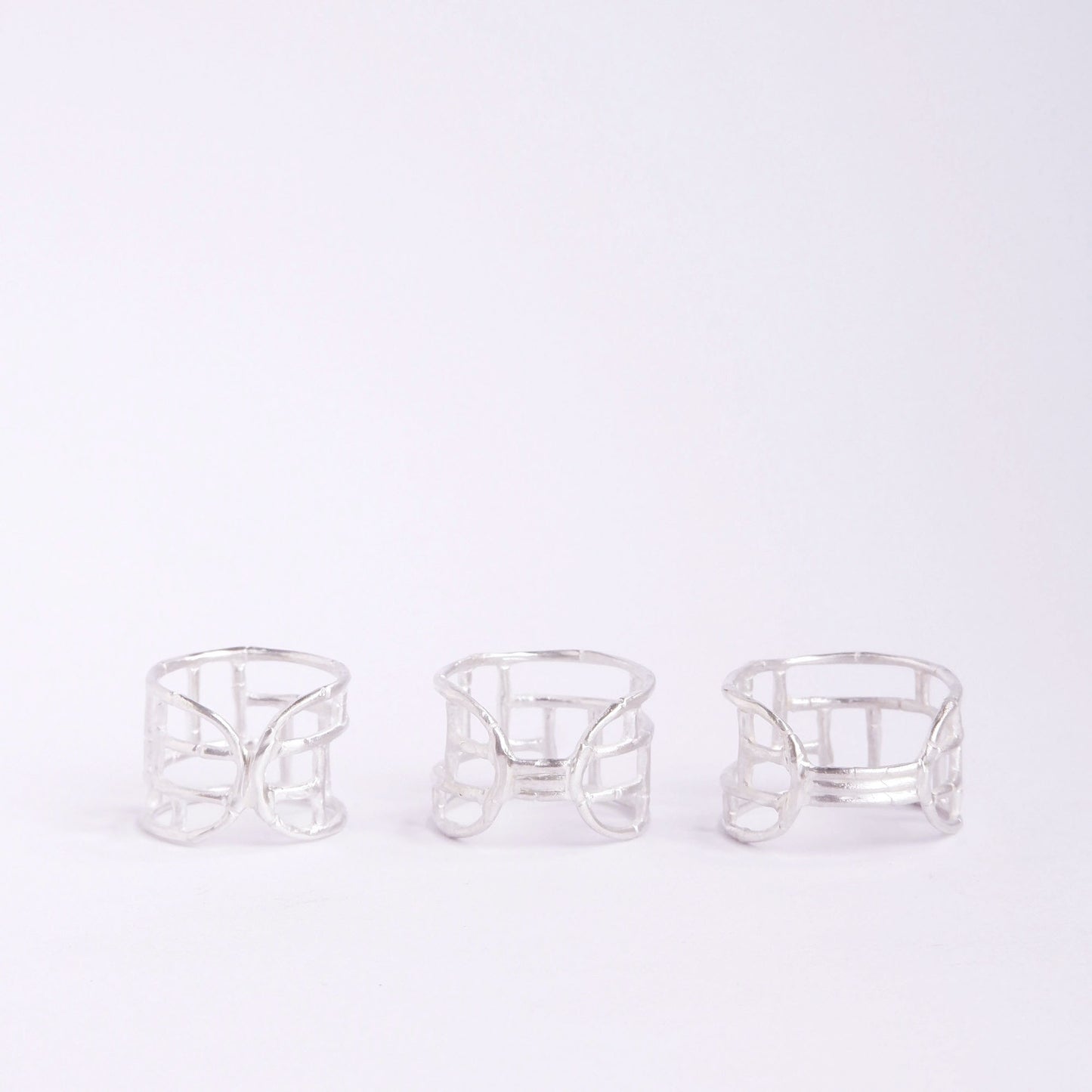 Three wide Sterling Silver rings with geometric open-work Bamboo screen design, on a white background