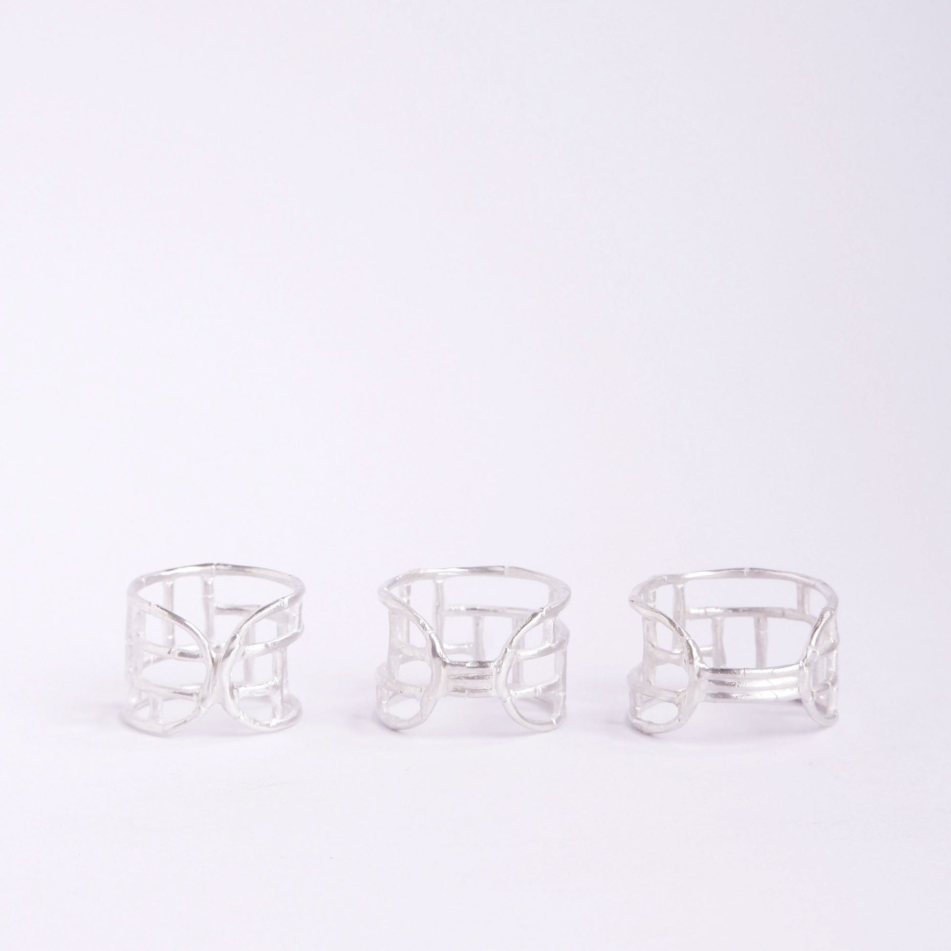 Three wide Sterling Silver rings with geometric open-work Bamboo screen design, on a white background