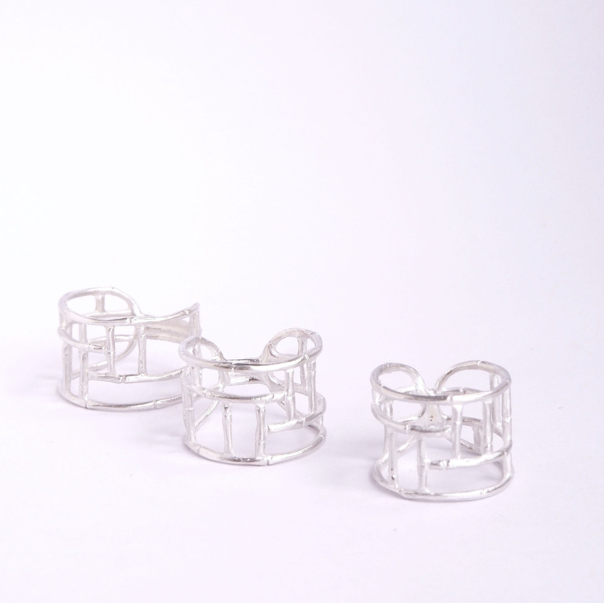 Three wide Sterling Silver rings with geometric open-work Bamboo screen design, on a white background