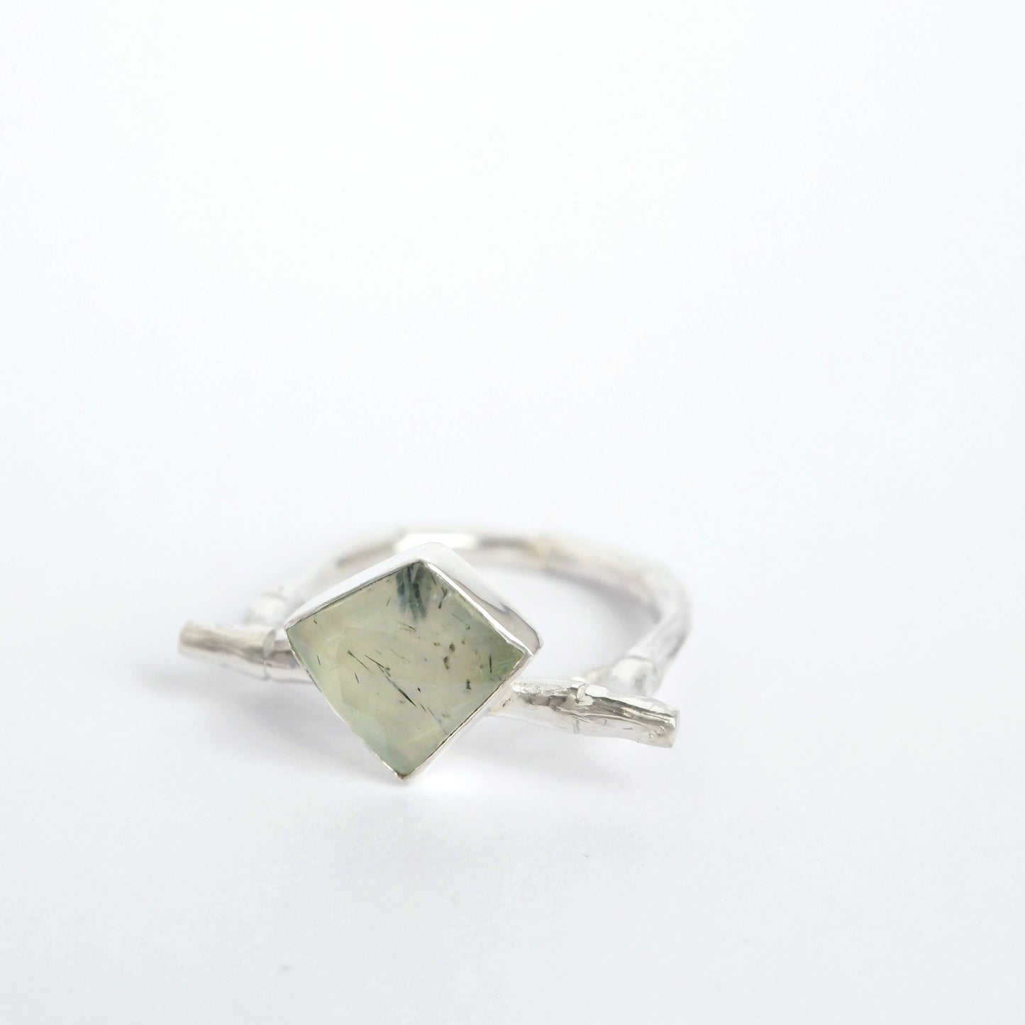 A Sterling Silver flat top bamboo style ring with an irregular angular geometric  Prehnite gem stone, on a white background