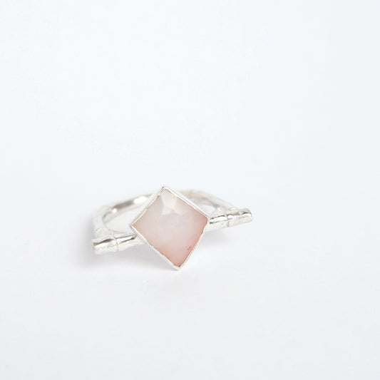 a Sterling Silver flat top bamboo style ring with a irregular angular geometric pale pink opal gem stone, on a white background