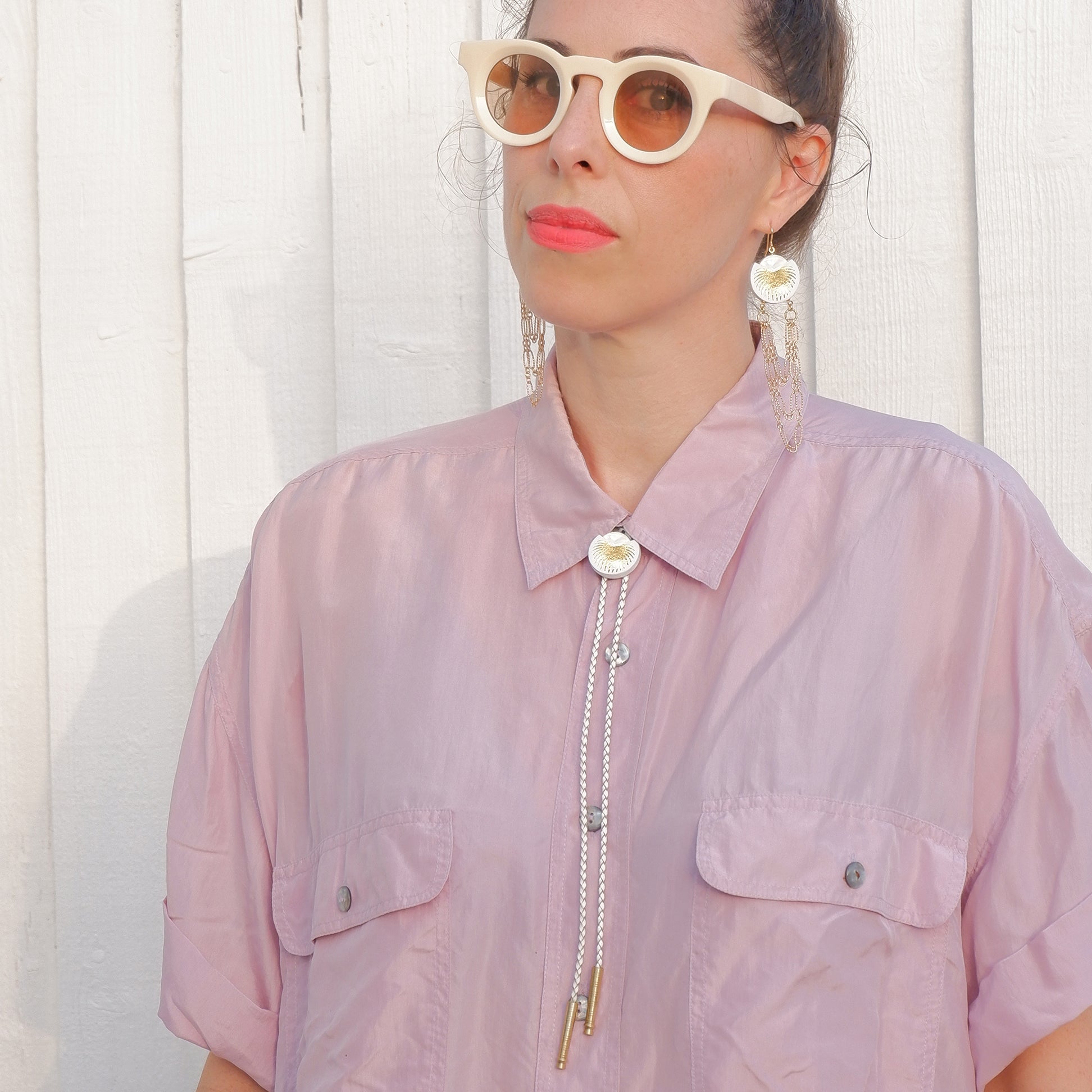 White leather bolo tie with gold palm print, mother of pearl accent & brass tips, on model in lilac shirt