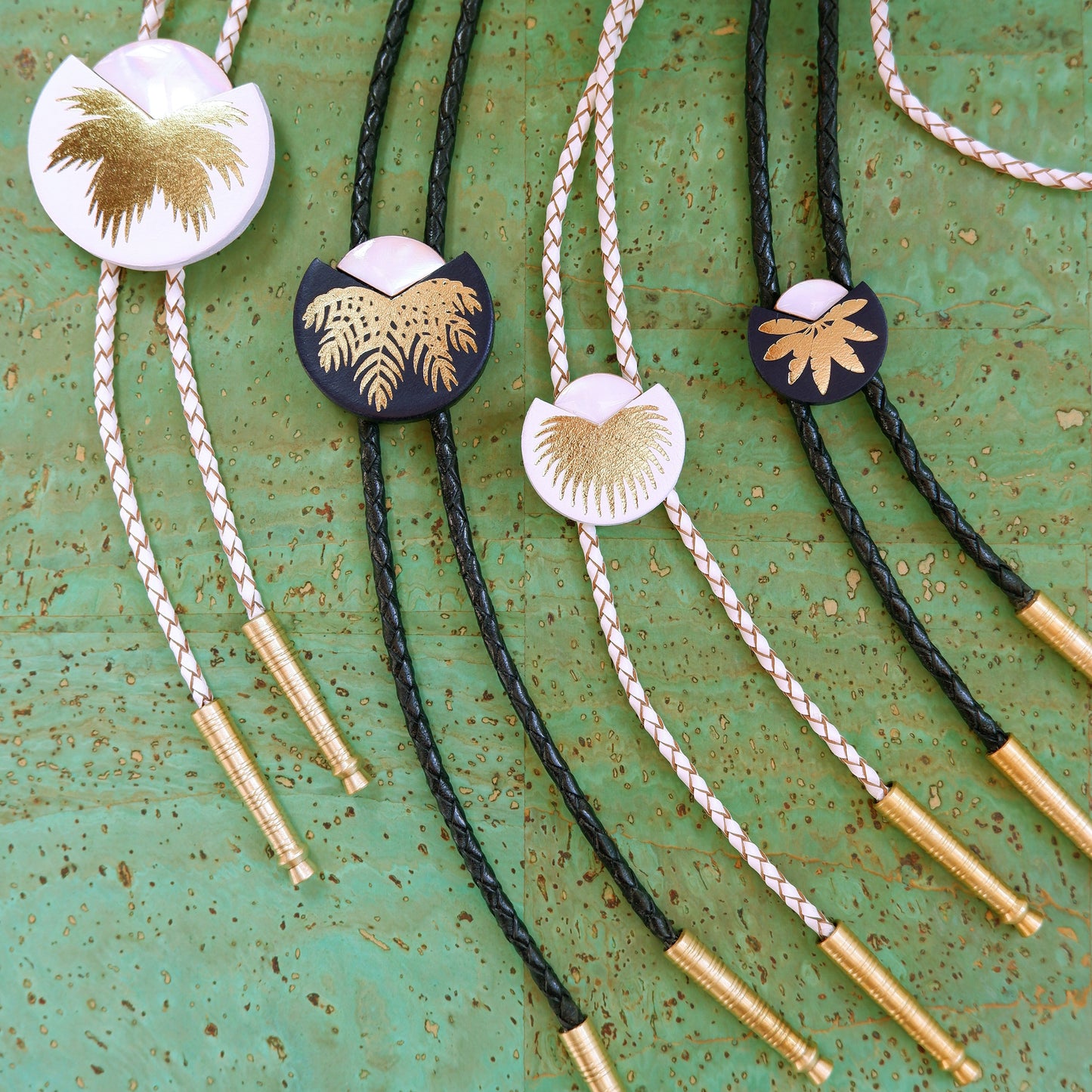selection of Black & White leather bolo ties with gold palm print, mother of pearl accent & brass tips