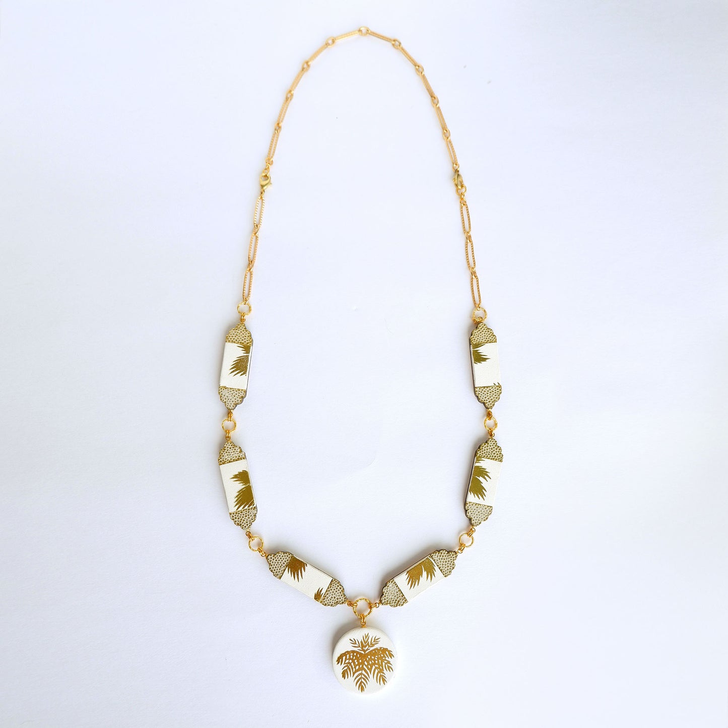 white leather necklace, with six sections & medallion pendant.. Gold Palm print on white leather, with embossed dot pattern detail., long