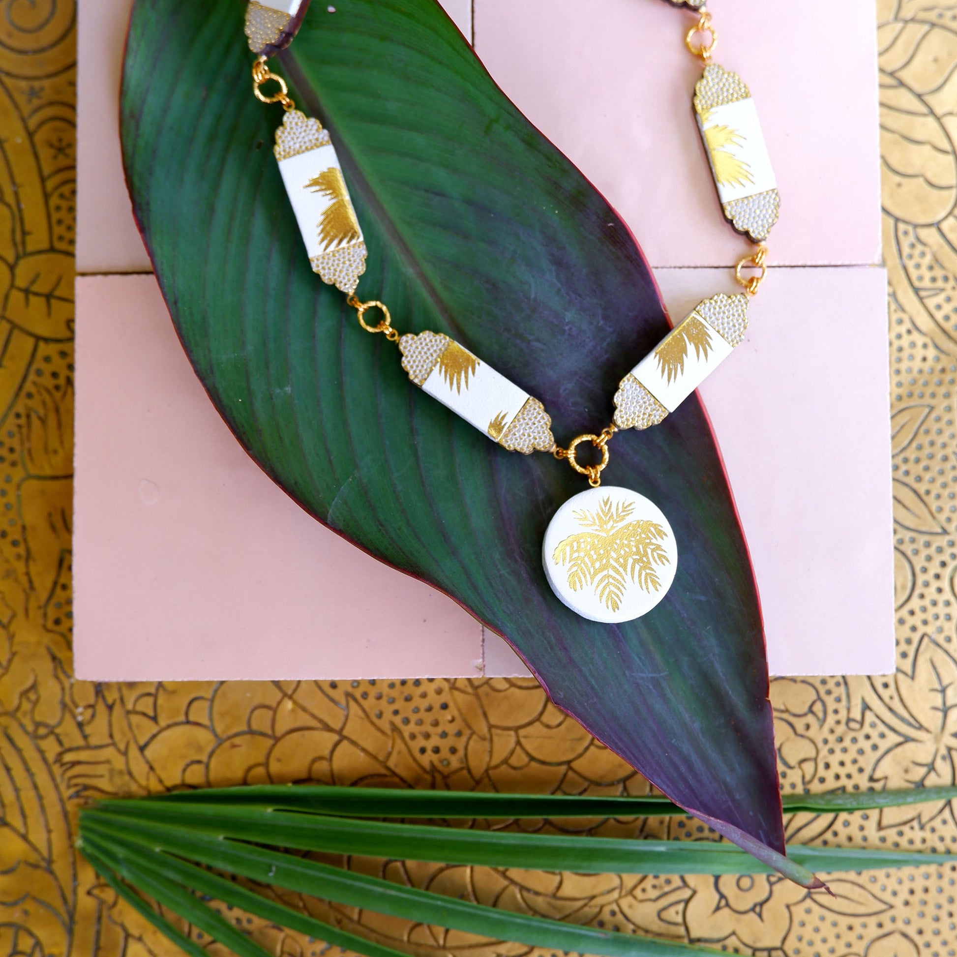 white leather necklace, with six sections & medallion pendant.. Gold Palm print on white leather, with embossed dot pattern detail., on tropical leaf