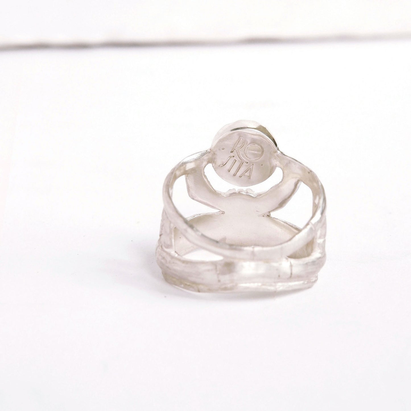 structural open-work ring in a bamboo style, featuring round central stone setting. Shown from the back/inside. Sterling Silver.
