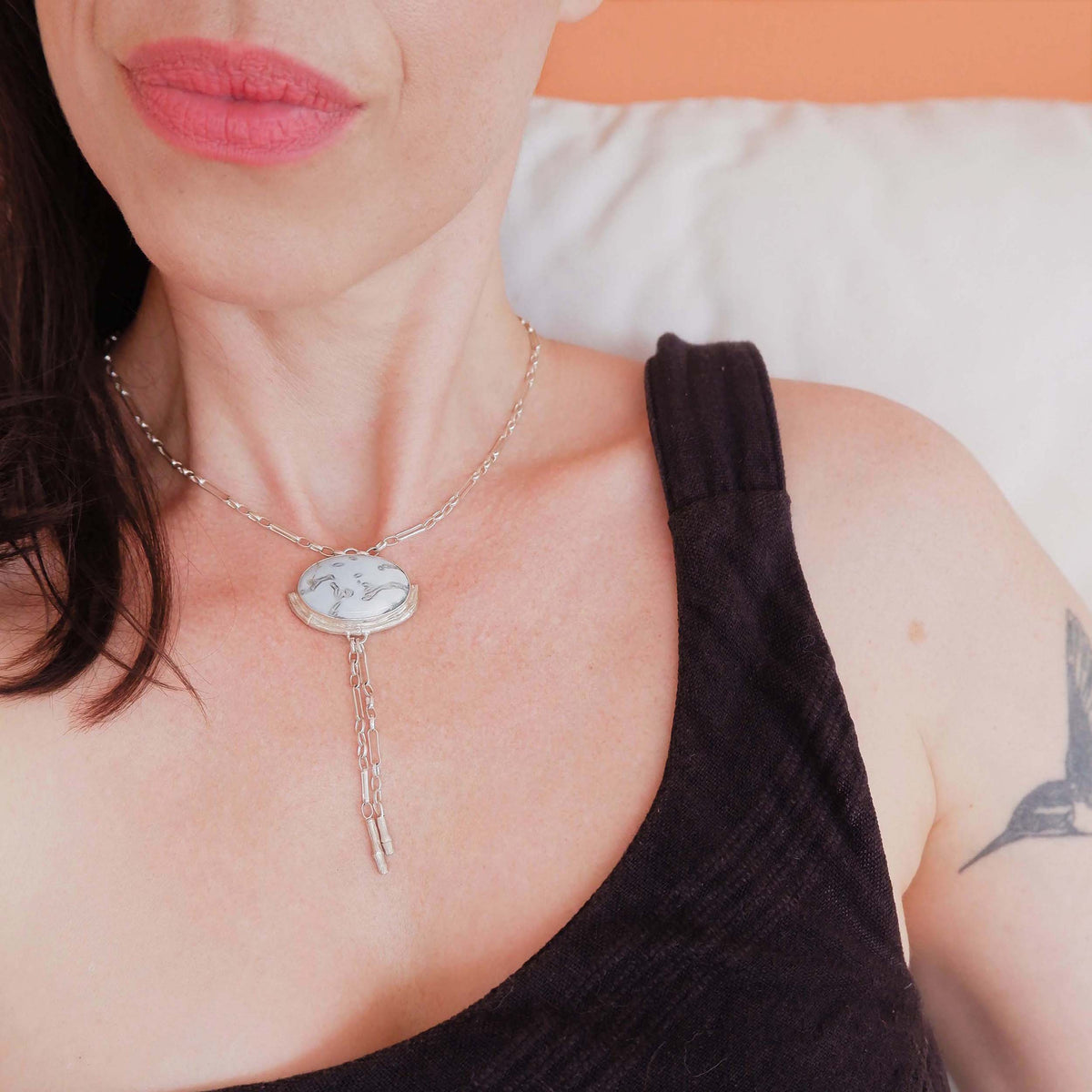 Silver Lariat style chain necklace, with a large marbled pale sky blue peruvian opal pendant, framed  by a hlaf halo of silver bamboo. On model.