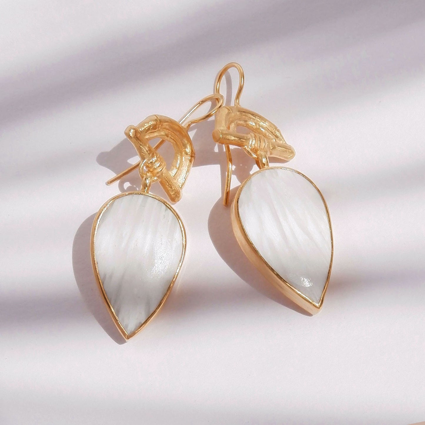 Gold Vermeil hook earrings featuring bamboo sunrise arch design, with pointed gemstone drop pendants in white scolecite, shown in bright sunlight
