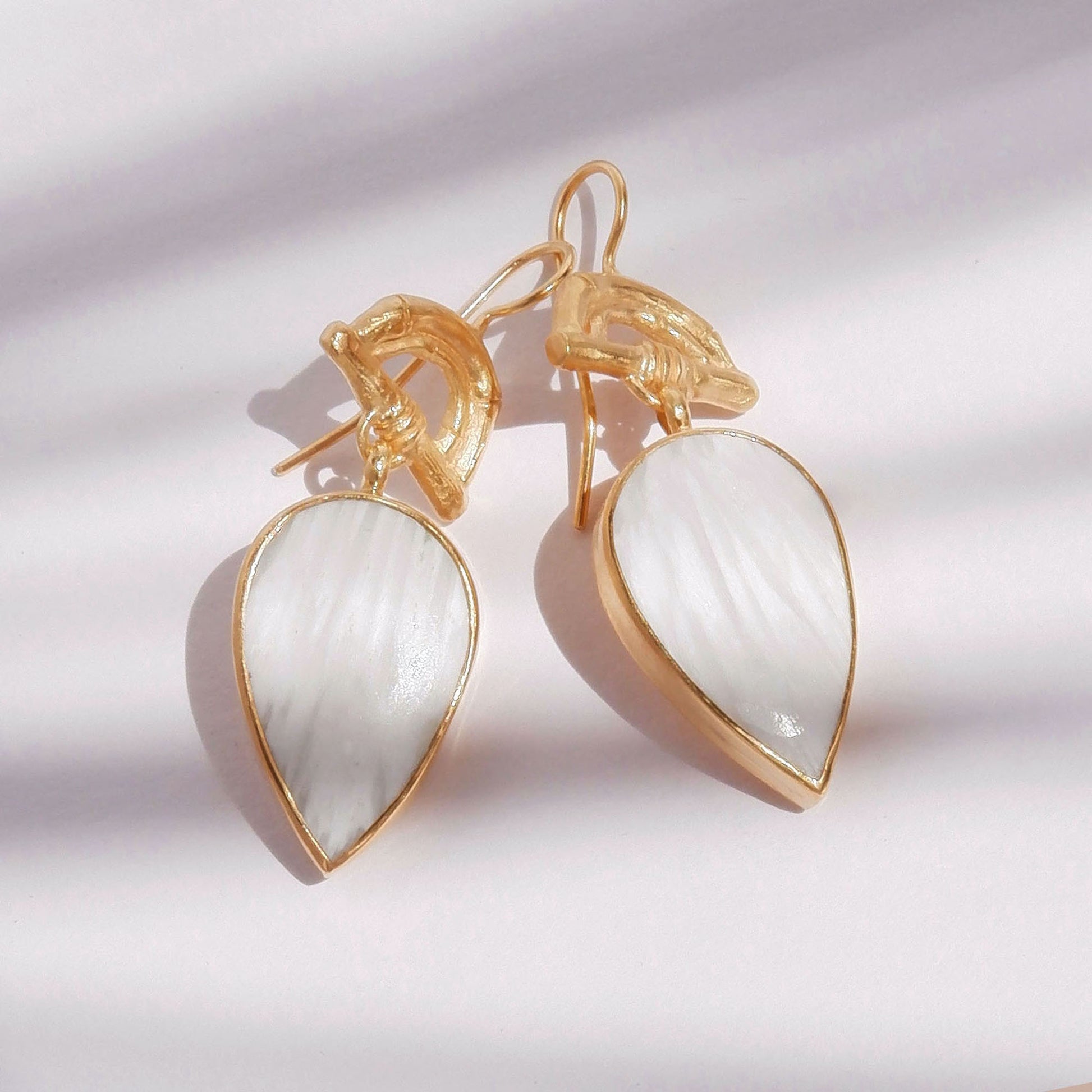 Gold Vermeil hook earrings featuring bamboo sunrise arch design, with pointed gemstone drop pendants in white scolecite, shown in bright sunlight