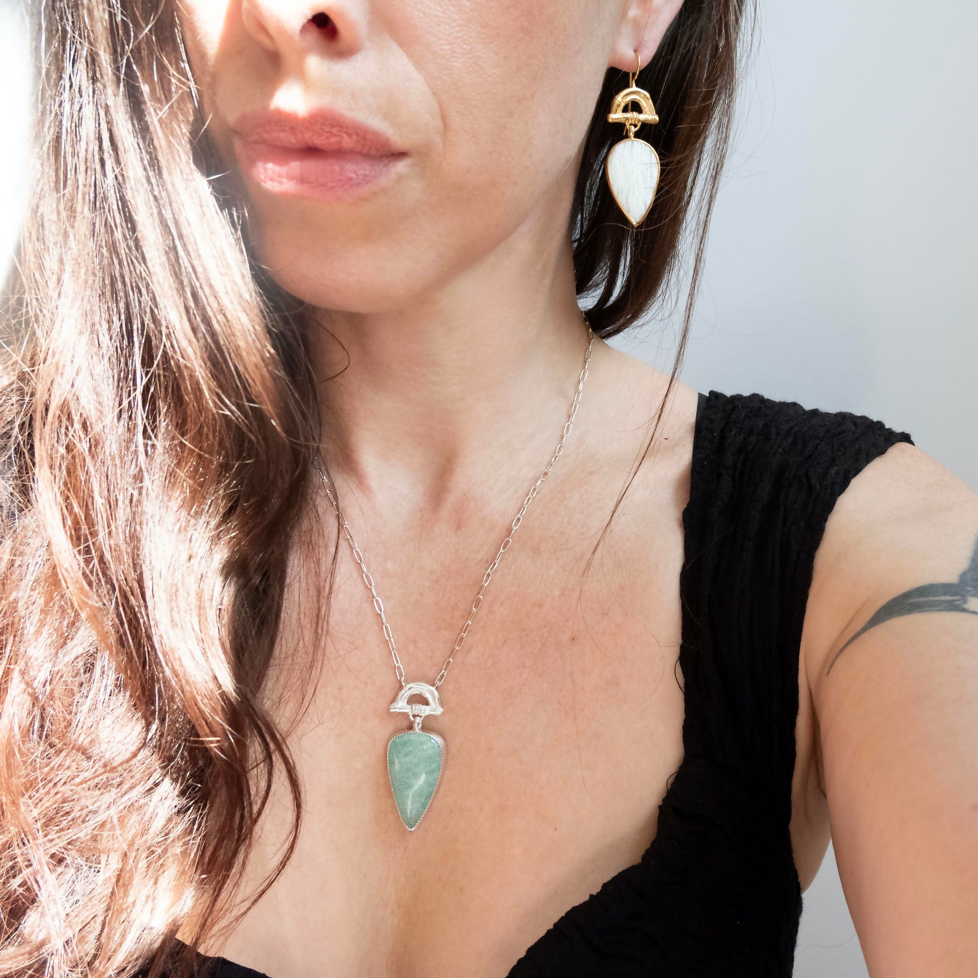 Pendant with  long pear-shaped Amazonite Gemstone hanging from silver Bamboo Arch, on fine silver chain. Shown on model with matching earrings in gold vermeil with white pear shaped gemstone