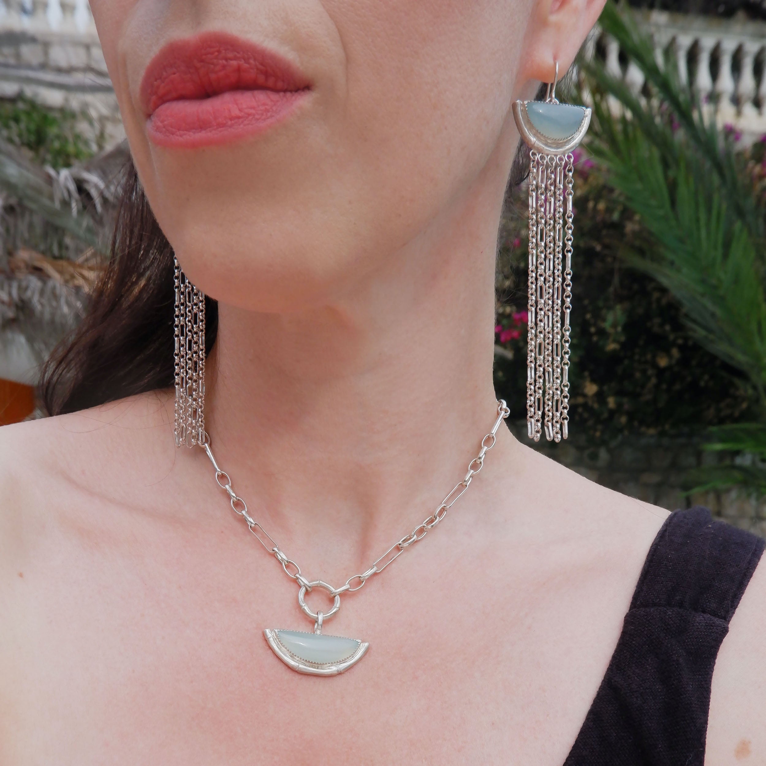 dramatic long chain fringe chandelier tassel earrings with half moon shaped semi precious Aqua Blue Chalcedony gemstones,  cupped by solid silver bamboo hammock, with simple silver wire hooks. Shown on model,, with matching aqua blue chalcedony half moon bamboo hammock necklace in sterling silver.