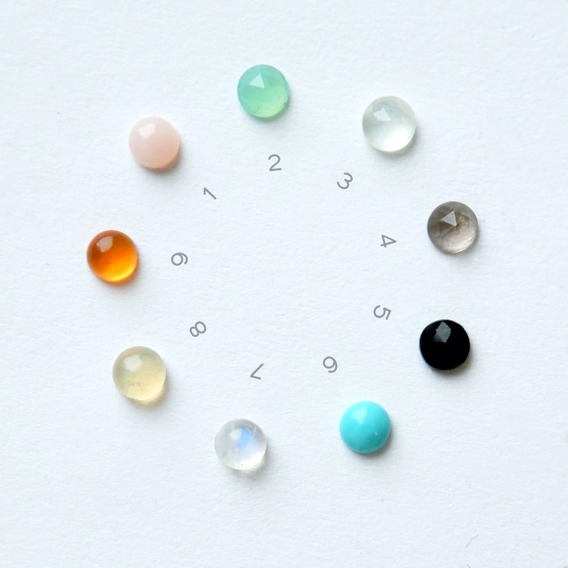 photograph of 9 little gemstones - the colour options for bombelli half moon squirrel drop earrings