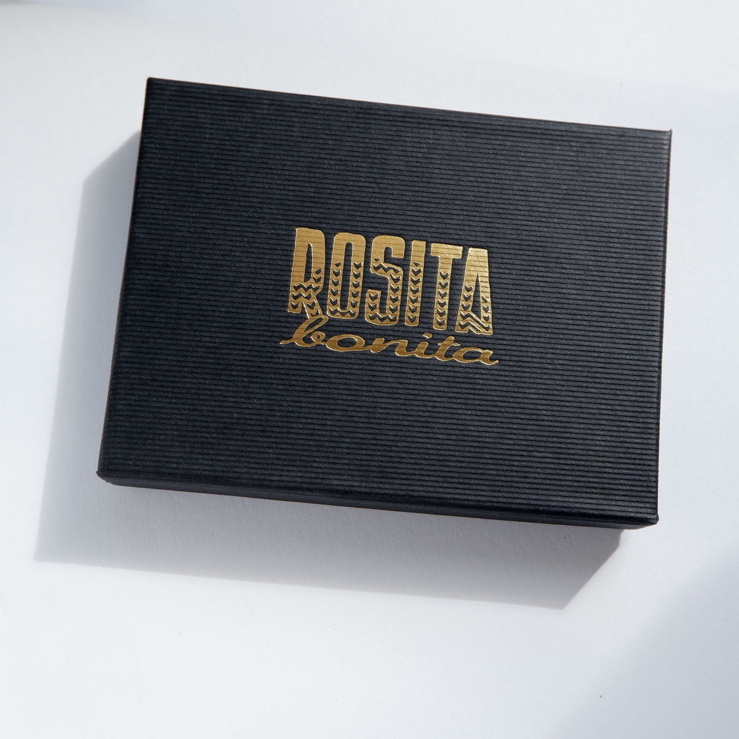 Black pinstripe cardboard box with Rosita Bonita logo in gold
