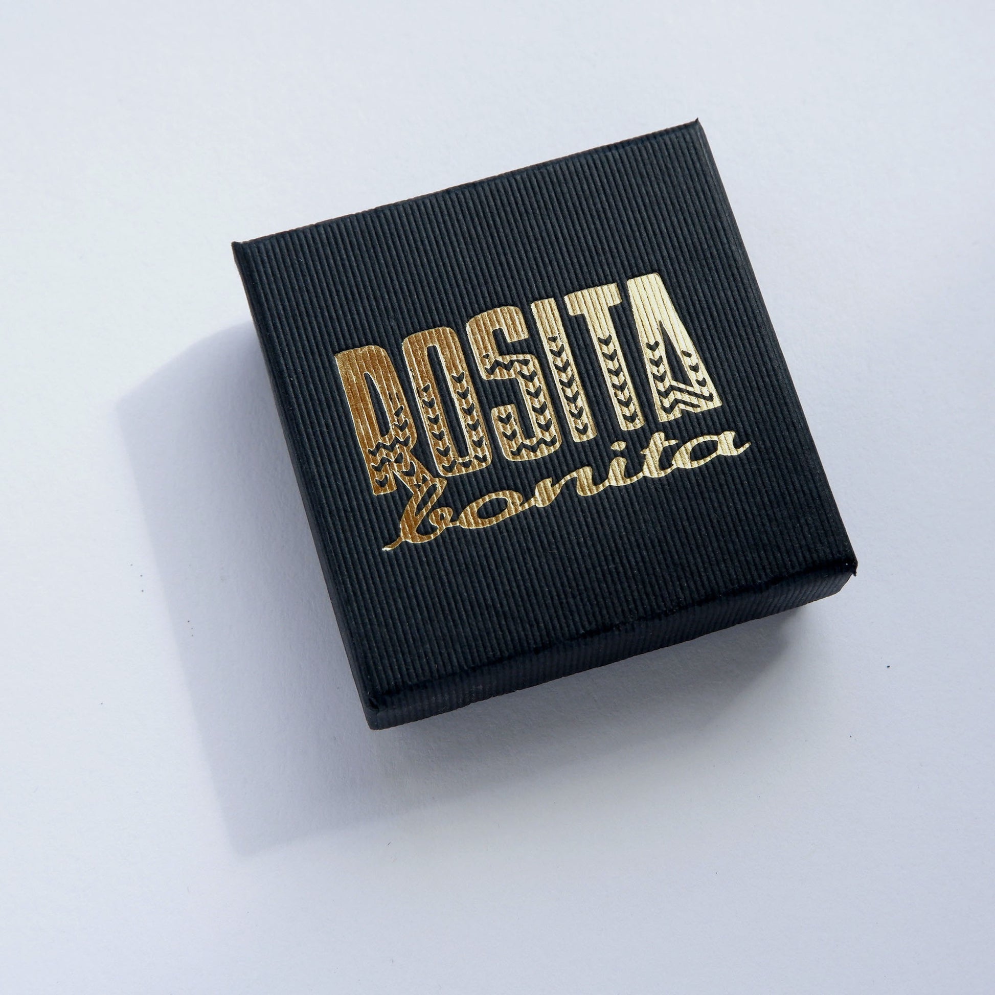 black ridged cardboard box with Rosita Bonita logo printed in gold