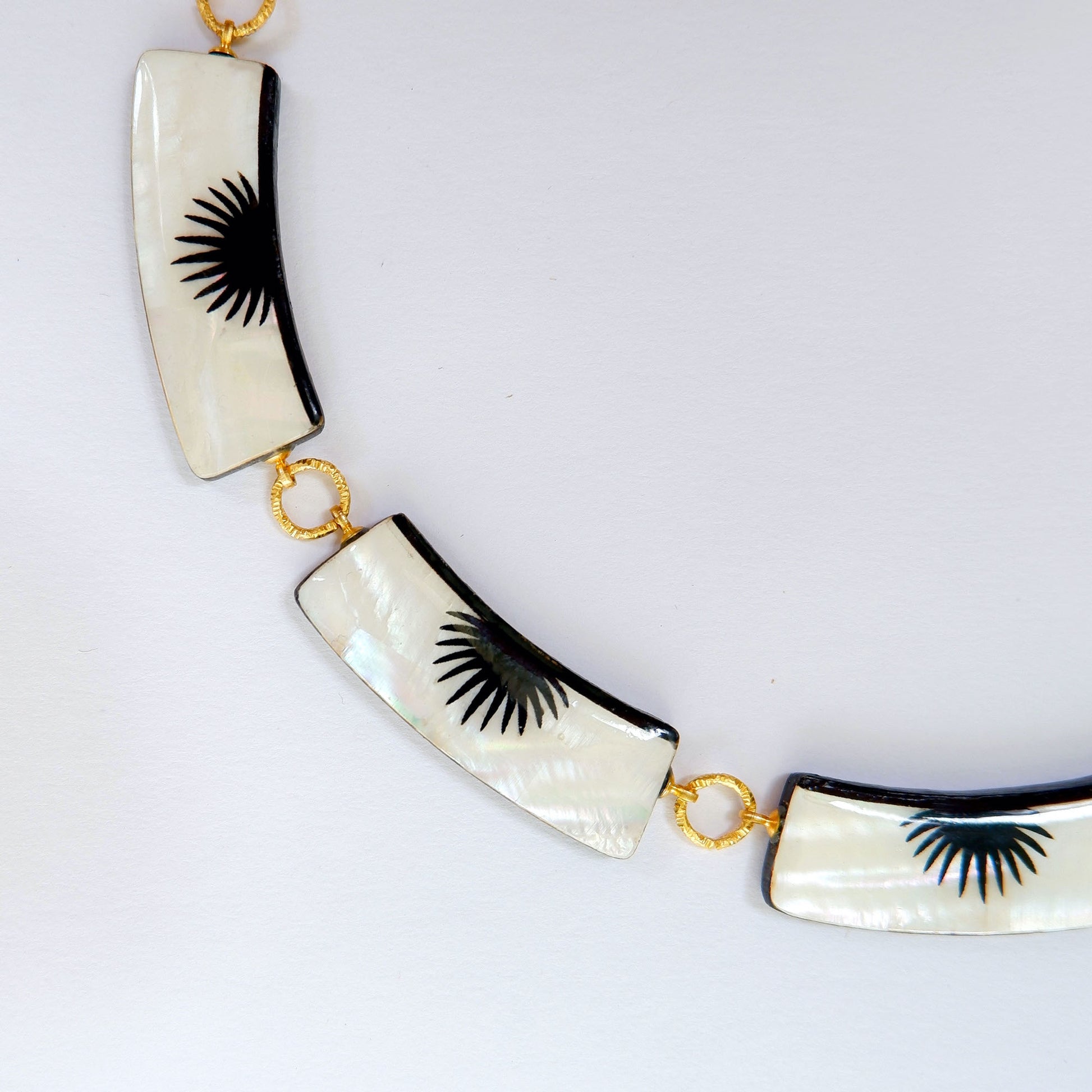 graphic black & white palm design mother of pearl necklace with 5 panels, on golden long-link chain close-up