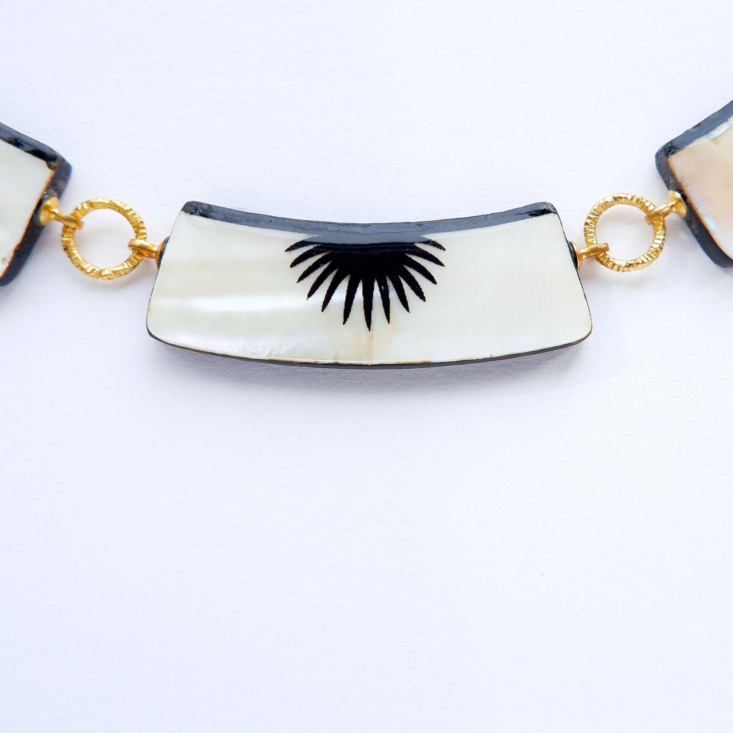 graphic black & white palm design mother of pearl necklace with 5 panels, on golden long-link chain, extreme close up