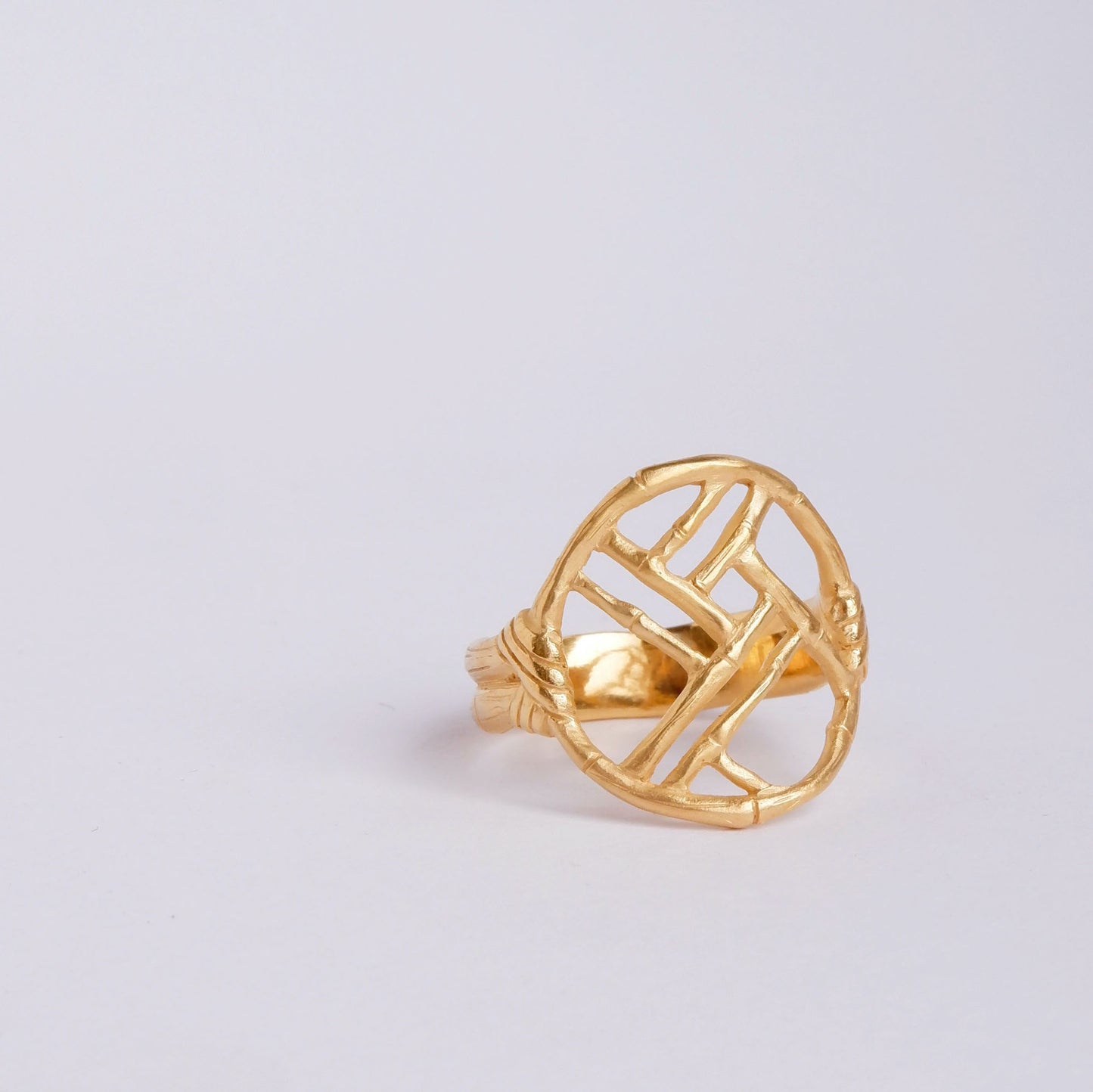 Gold ring with geometric open-work Bamboo Circle screen design, on a white background