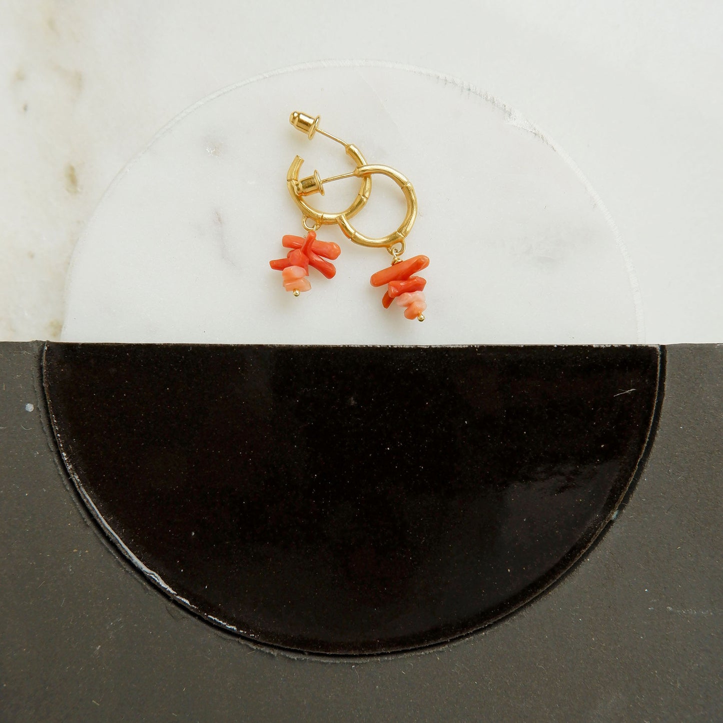 small gold bamboo hoops, with stacked coral branch bead charms, still life with marble and ceramaic tiles