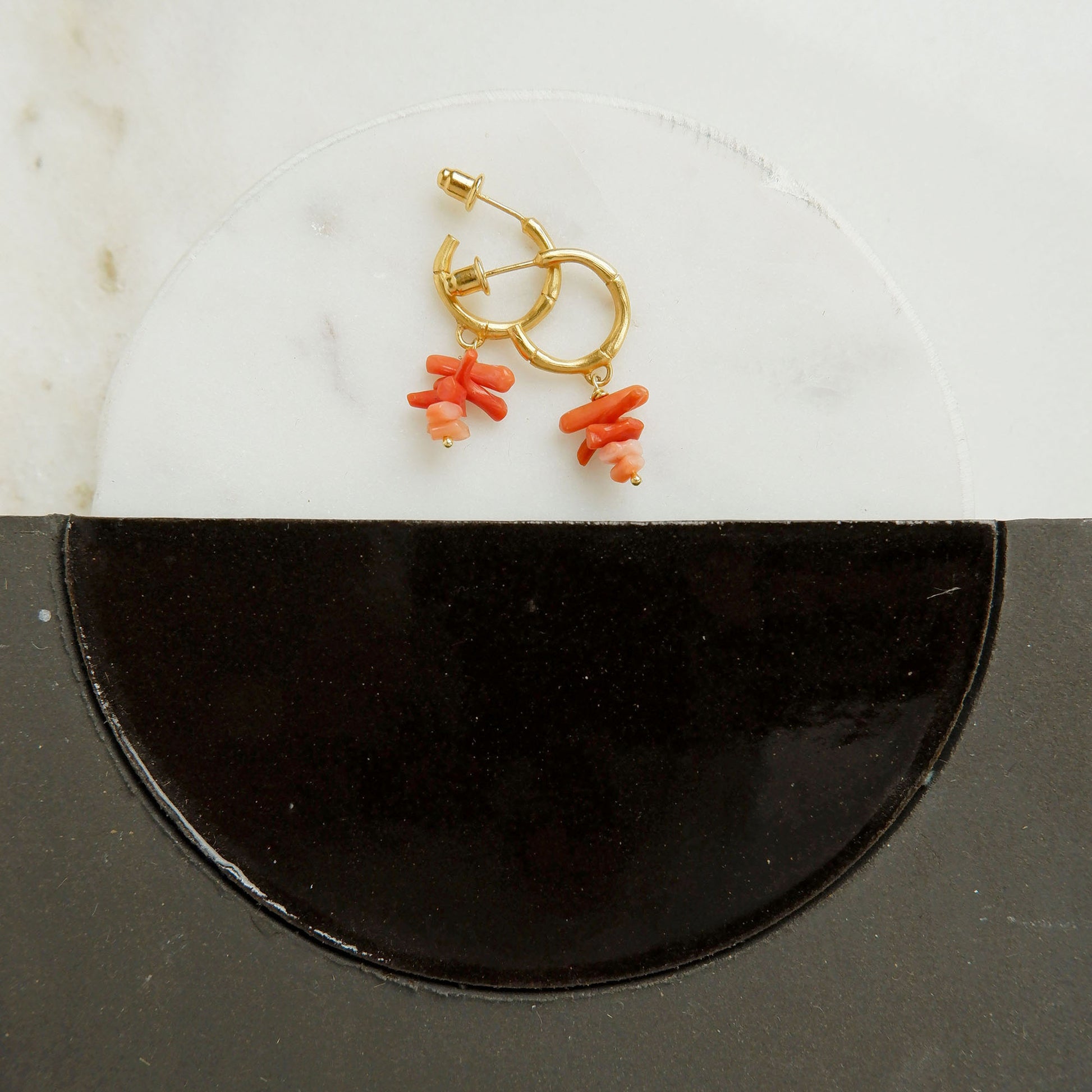 small gold bamboo hoops, with stacked coral branch bead charms, still life with marble and ceramaic tiles