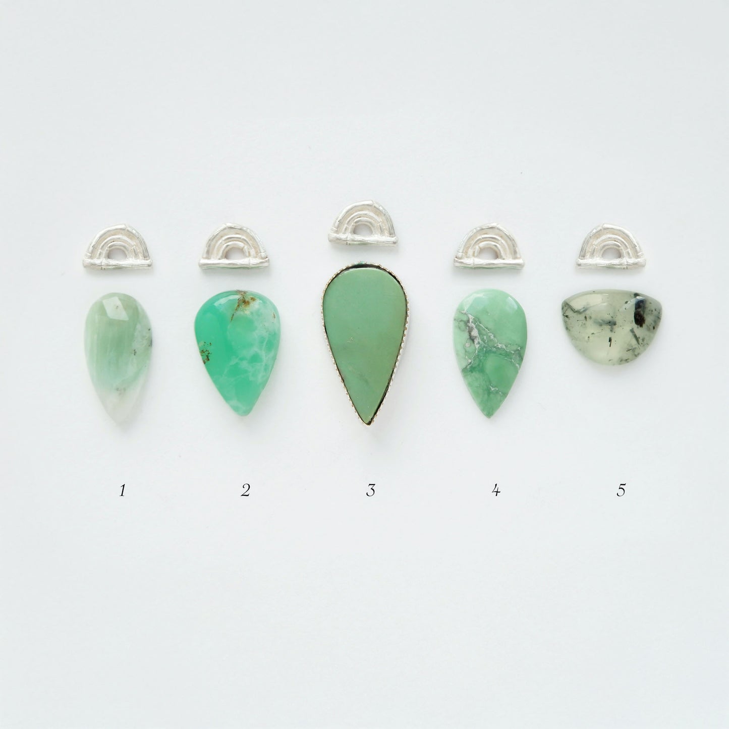 Five green teardrop pendants with silver arches on a white background
