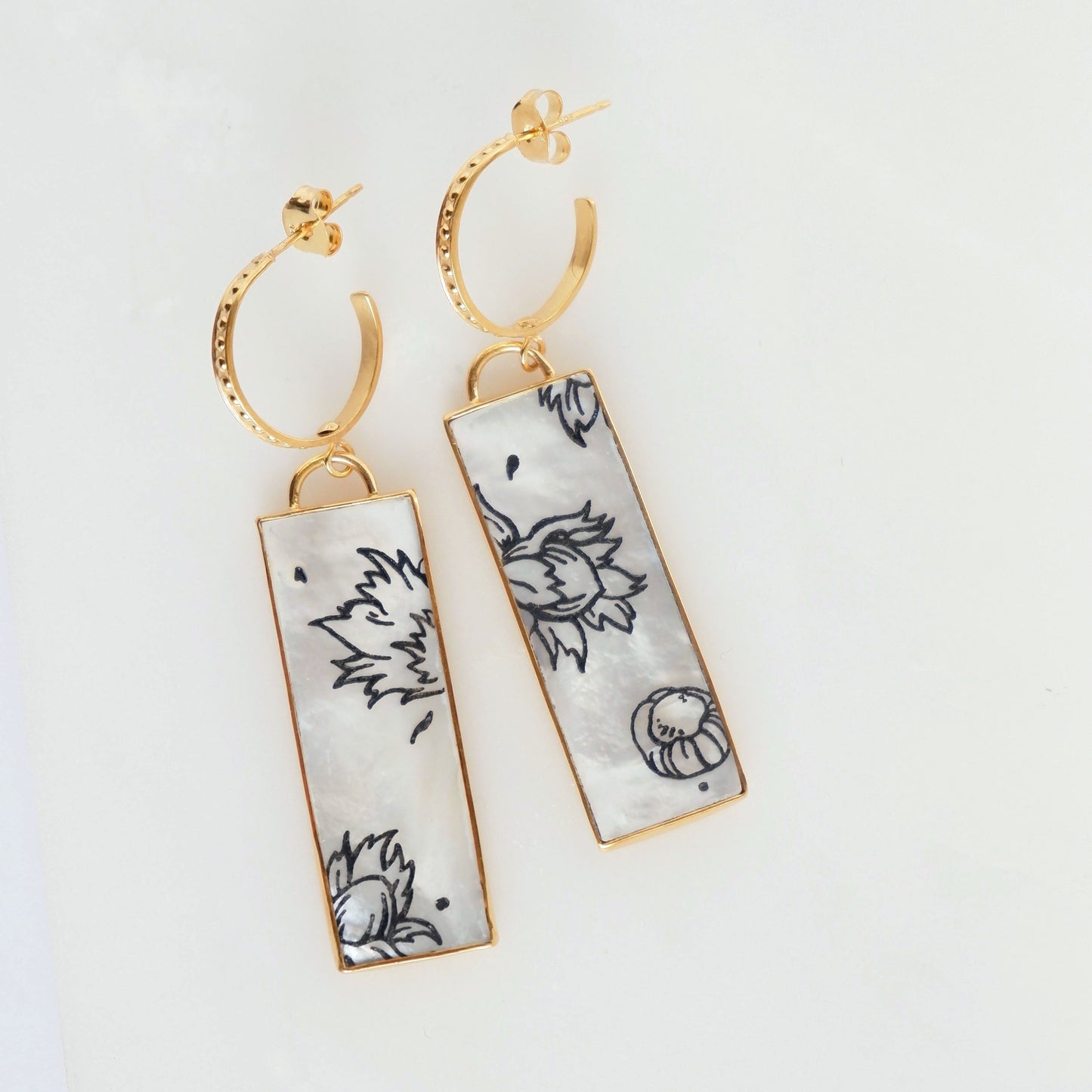 dotted gold hoop earrings with large rectangular drop pendants in Mother of pearl, engraved with graphic botanical cobnut design