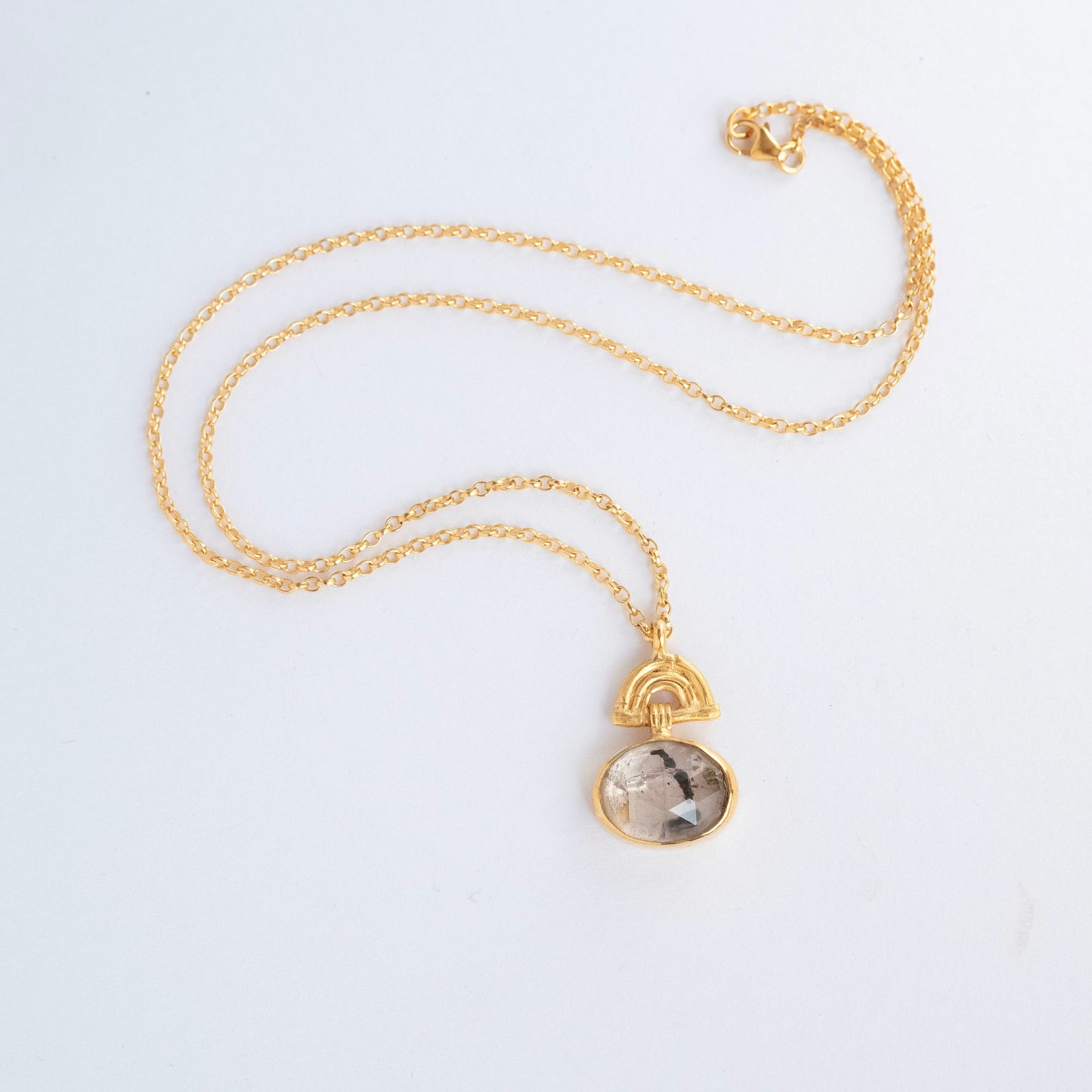 Pendant with oval Tourmalated Rose Quartz Gemstone hanging from a small gold Bamboo Arch, on fine gold chain. white background