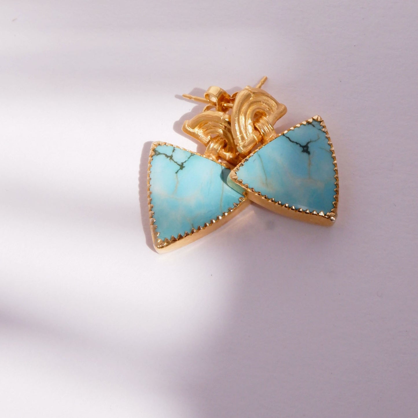 small stud earrings in gold vermeil, featuring triple arches of bamboo, hung with  triangular turquoise gemstone charm pendants, set with gold teeth.