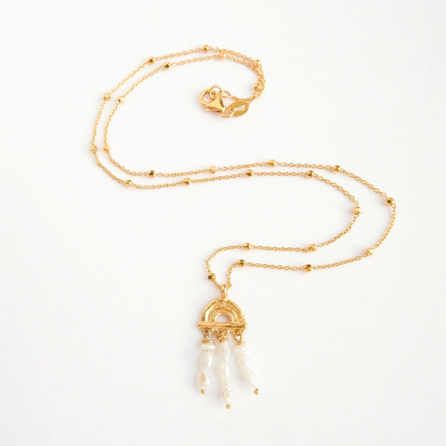 small pendant necklace in Gold Vermeil, featuring a triple arch of bamboo, adorned with short strings of freshwater pearls, on a faceted beaded satellite chain.